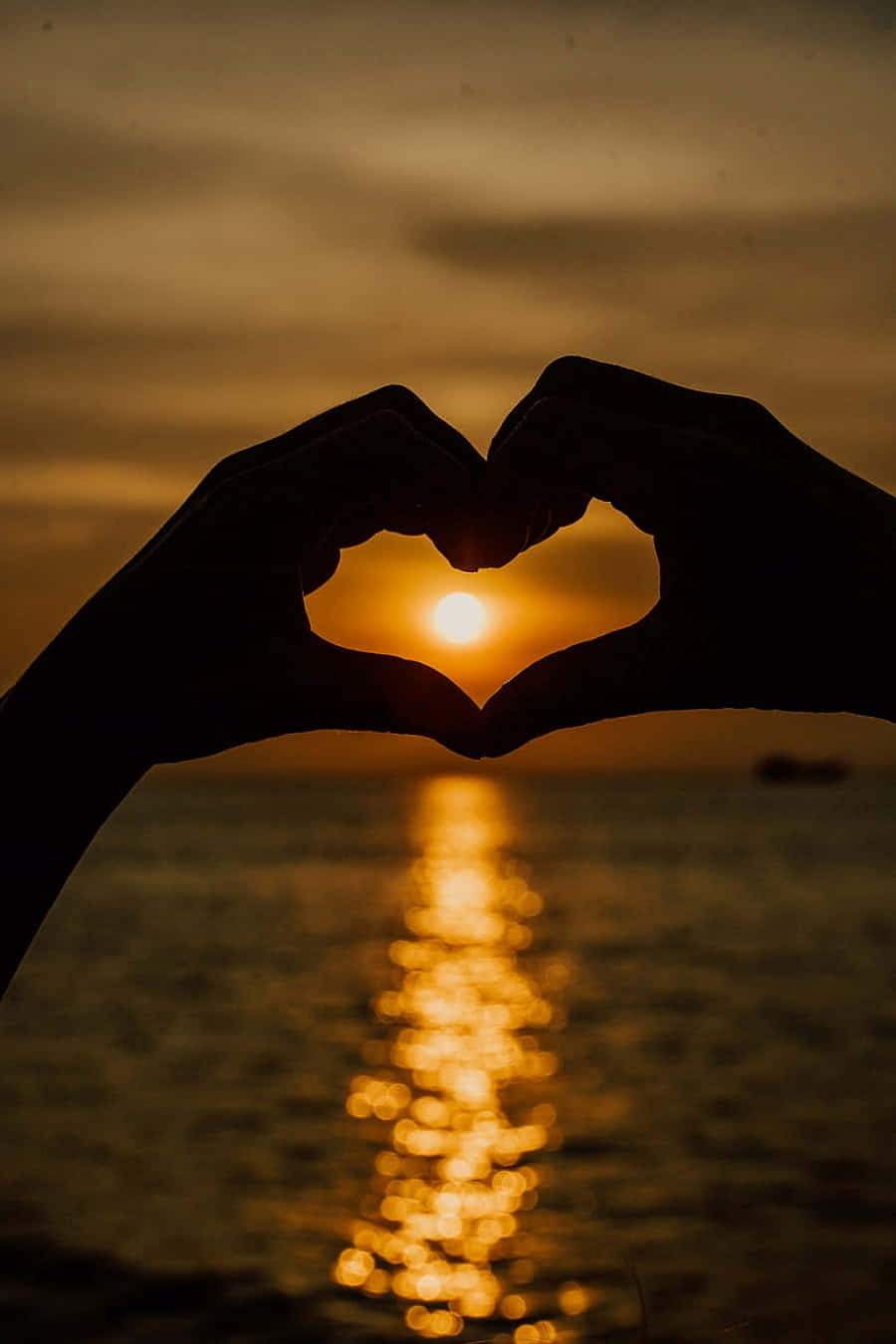 Heart Silhouette 桌布 壁紙 — 剪影雙手形成心形，框住閃爍水面上發光的日落。