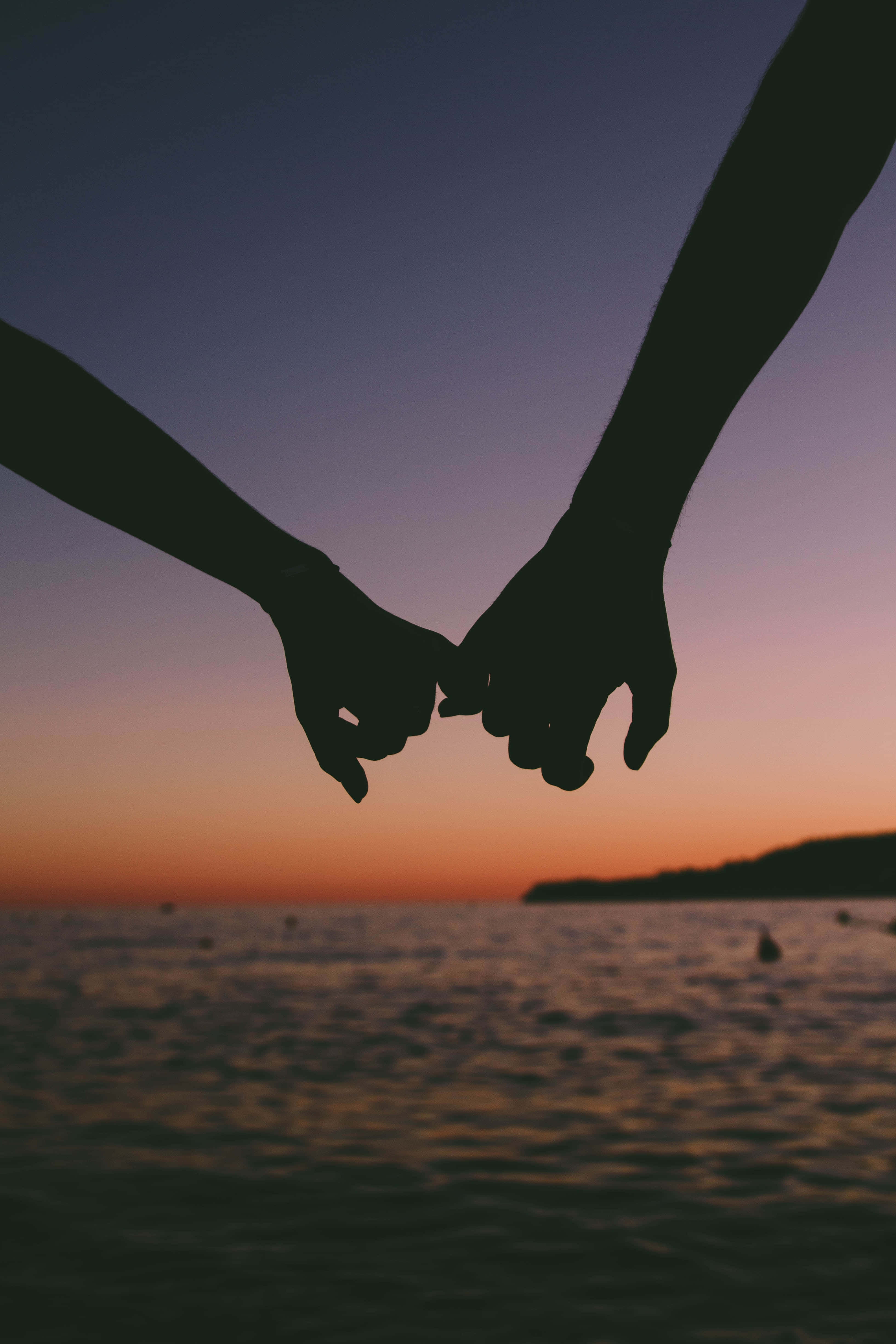 Relationship 桌布 壁紙 — 剪影雙手緊握，背景是平靜海洋上 vibrant 的日落。