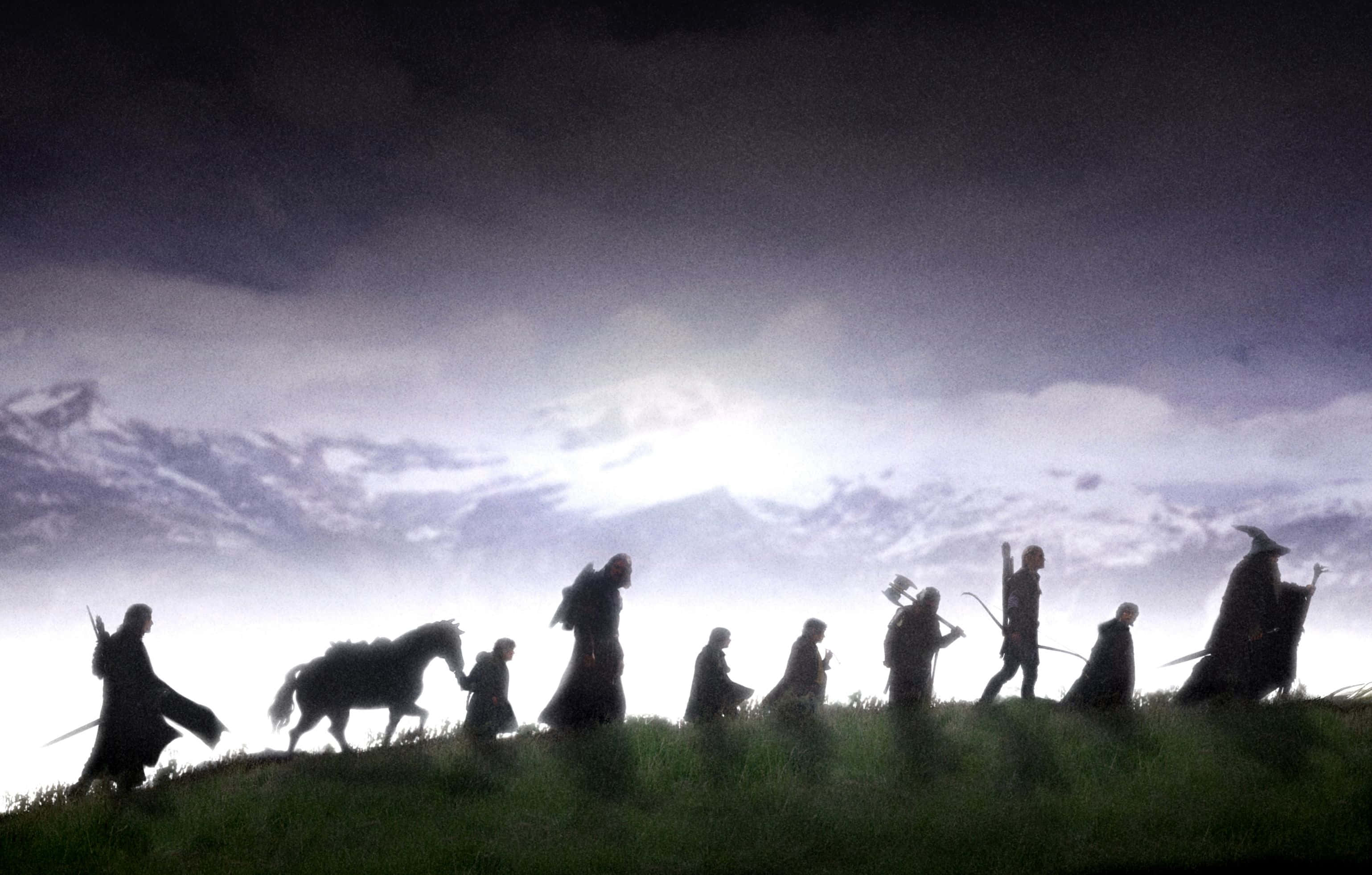 Lotr 桌布 壁紙 — 剪影風格的奇幻冒險者和一匹馬在戲劇性的暮色天空下穿越草嶺。