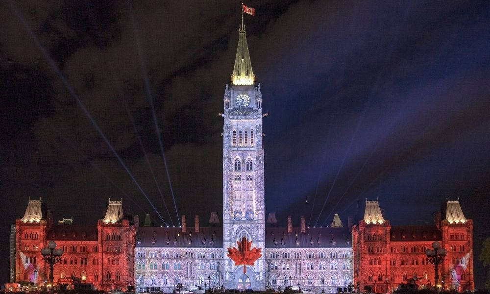 Light 桌布 壁紙 — 加拿大國會大廈在夜間被紅燈照亮，外牆上有巨大的楓葉投影。