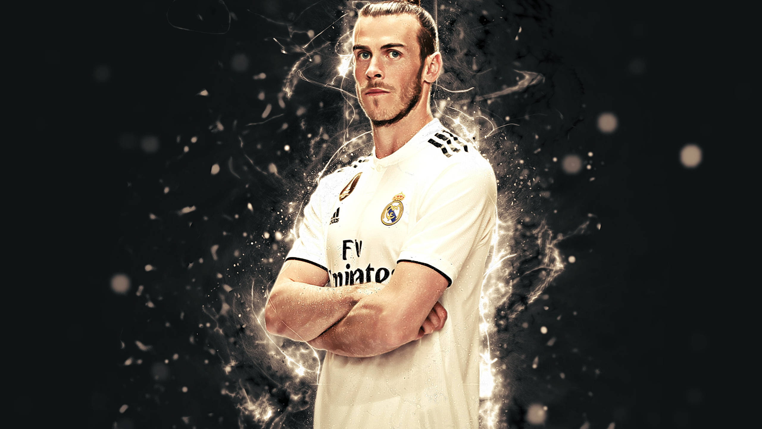 Gareth Bale 桌布 壁紙 — 加雷斯貝爾自信地站在深色背景前，雙臂交叉，身穿皇家馬德里球衣，周圍有發光粒子效果。