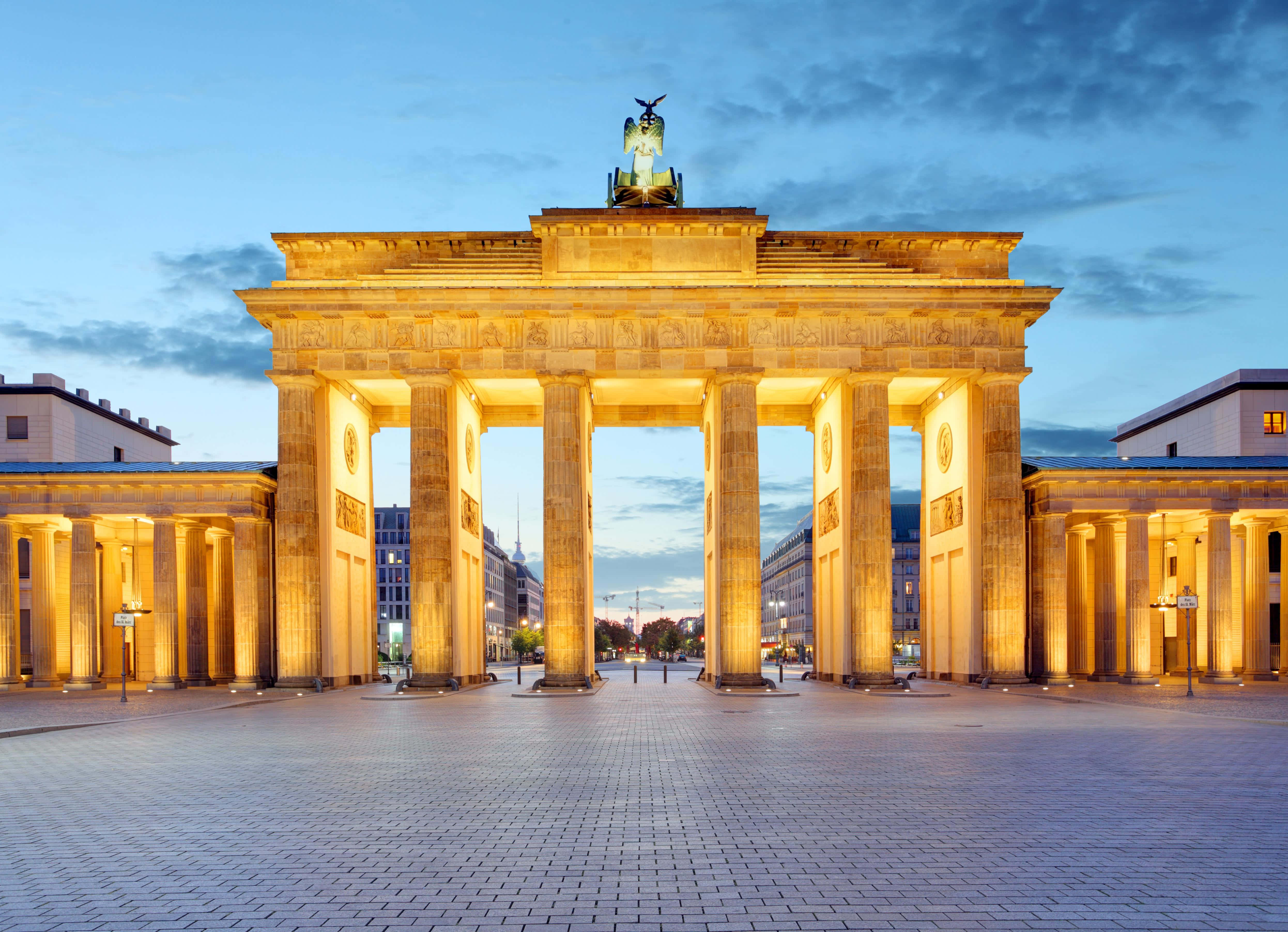 Berlin 桌布 壁紙 — 勃蘭登堡門在溫暖金色燈光下，襯托著帶有散雲的暮色天空。