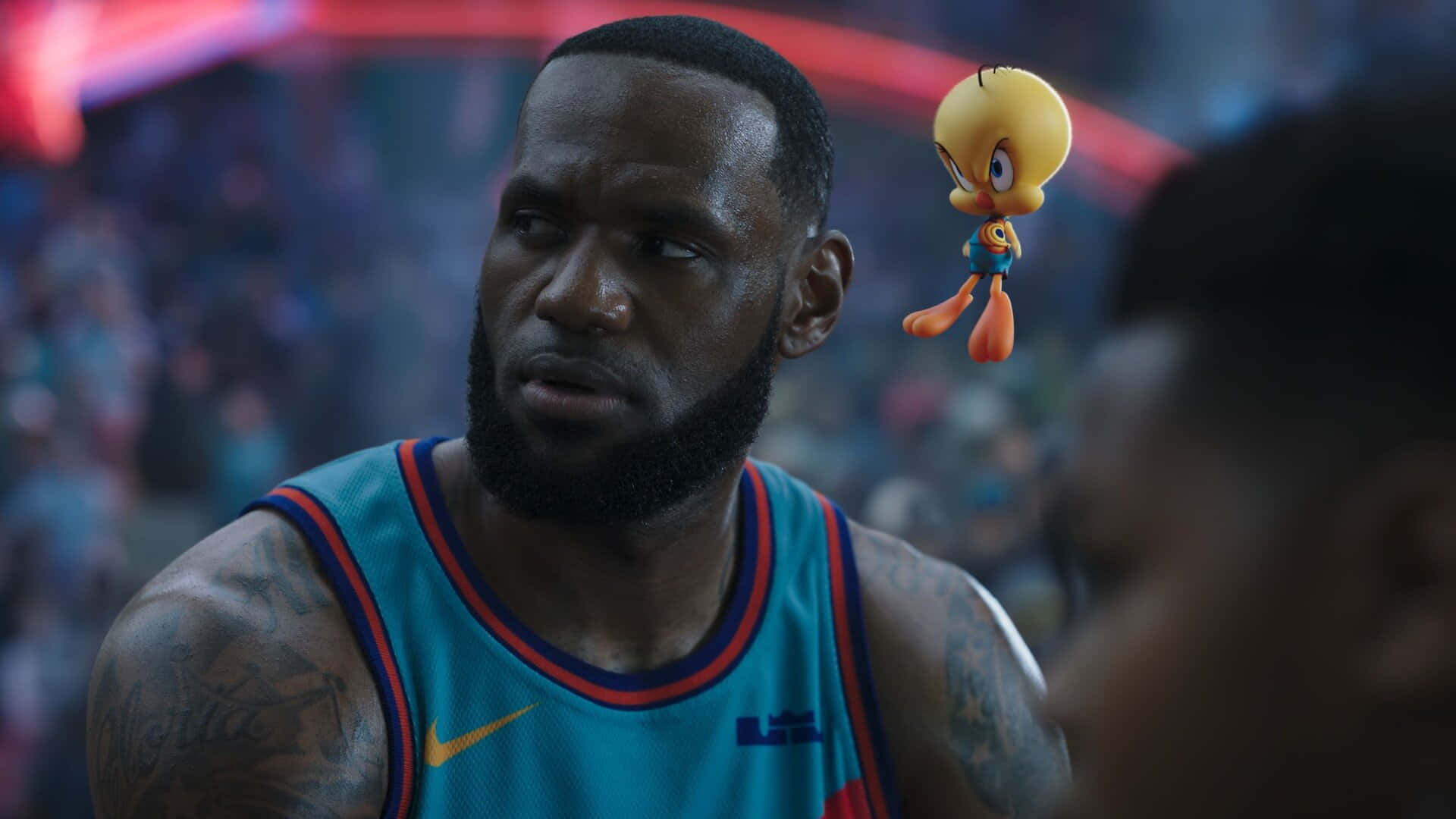 Cool Space Jam 桌布 壁紙 — 勒布朗·詹姆斯身穿青綠色籃球球衣，在擠滿人的場館內凝視著漂浮在頭旁的卡通崔弟鳥。