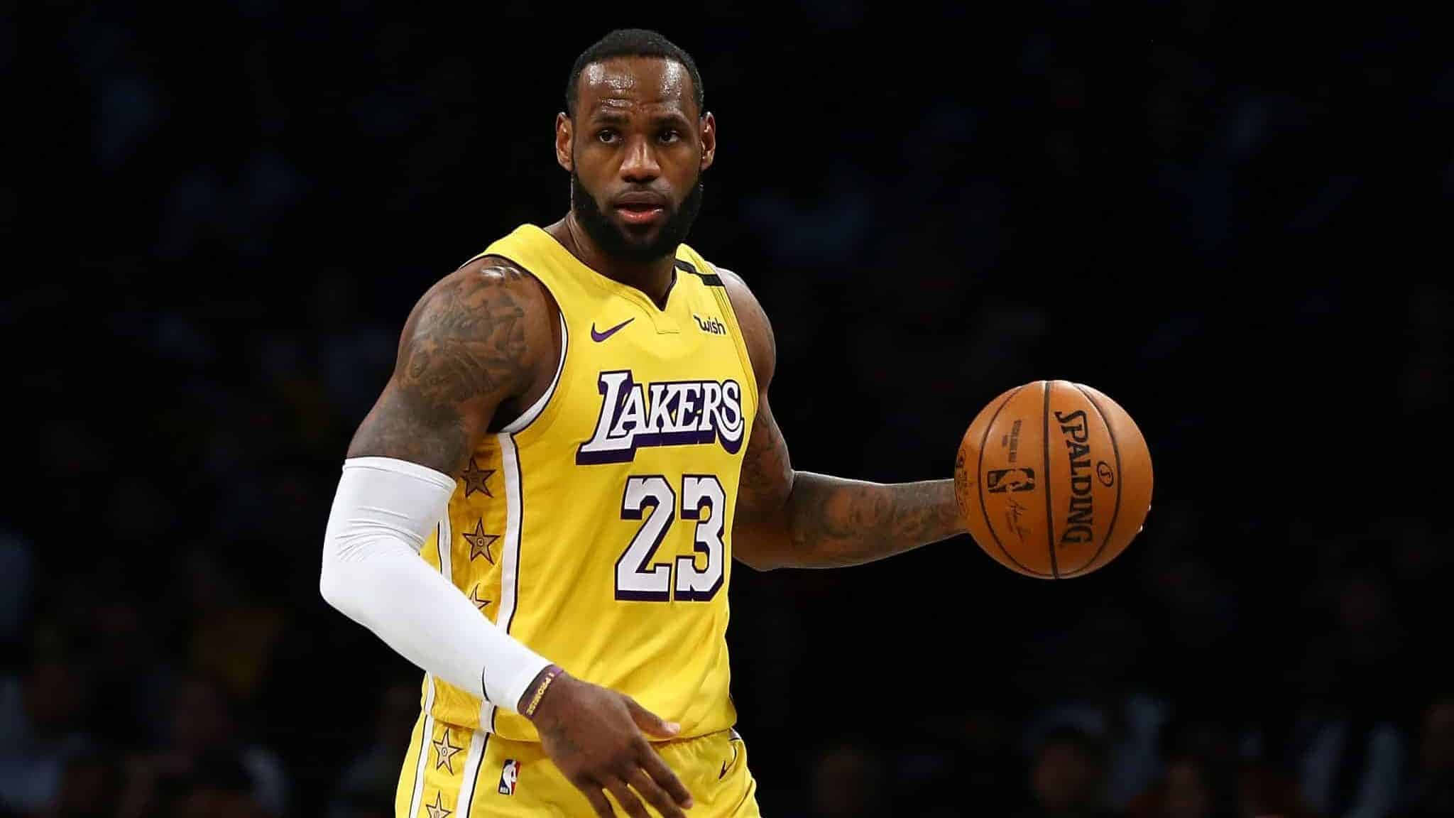 Lebron And Kobe 桌布 壁紙 — 勒布朗·詹姆斯身穿黃色湖人球衣，在場館燈光下專注地運球，充滿強烈氣勢。