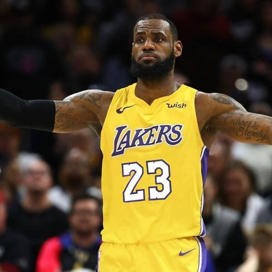 Lebron James Lakers 桌布 壁紙 — 勒布朗·詹姆斯身穿黃色湖人隊23號球衣，在場館燈光下於籃球比賽中張開雙臂站立。