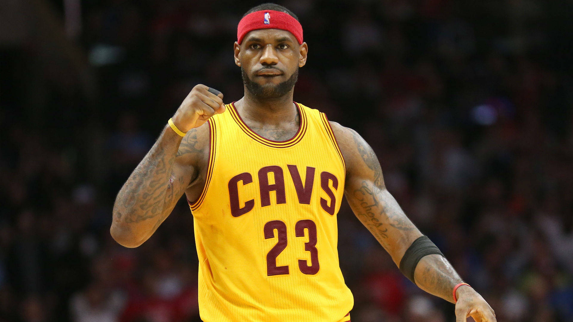 NBA 桌布 壁紙 — 勒布朗·詹姆斯身穿黃色騎士隊球衣在場館內舉起拳頭，身後是模糊的人群。