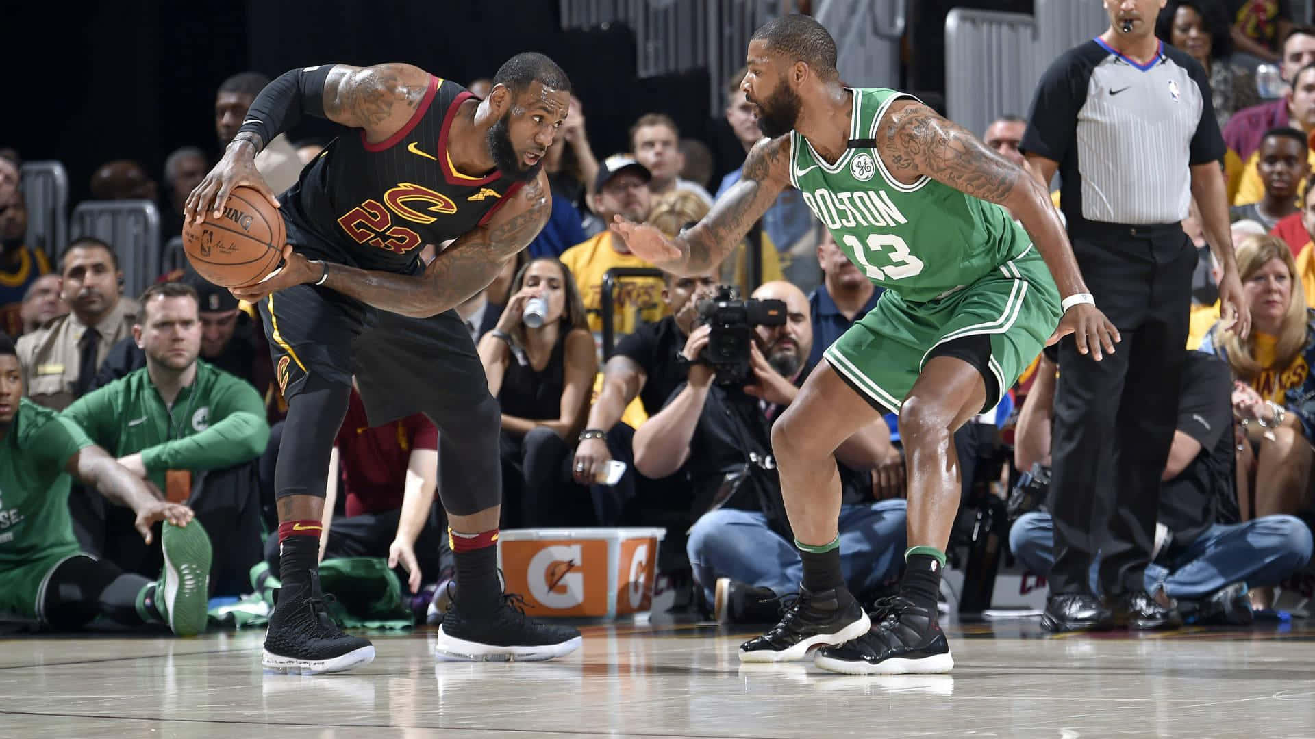 NBA 桌布 壁紙 — 勒布朗·詹姆斯身穿黑色球衣，在明亮的場館燈光下，於激烈的NBA比賽中帶球突破綠色球衣的波士頓塞爾提克防守球員。