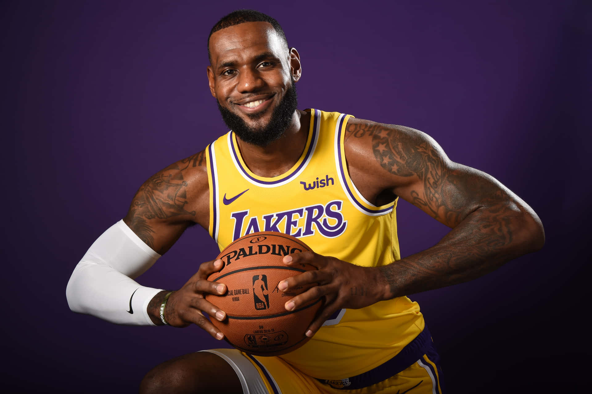 勒布朗詹姆斯身穿湖人球衣，在紫色背景下持球。 — NBA 壁紙