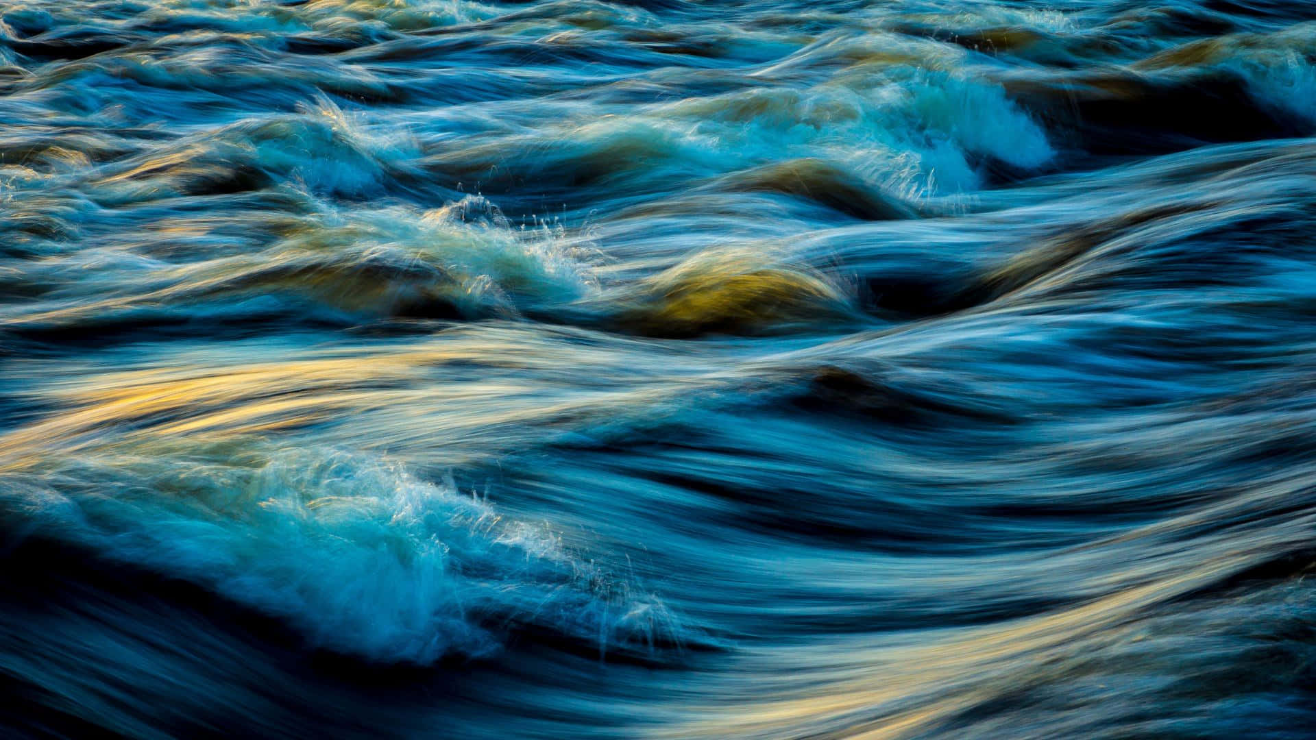 waves 桌布 壁紙 — 動態抽象水流動，帶有藍色和金色光線條紋，形成流暢的紋理圖案。