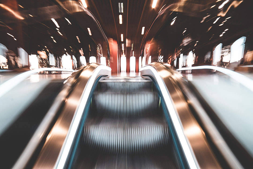 Moving 桌布 壁紙 — 動態模糊視角，顯示現代交通站內向上移動的自動扶梯，帶有光線條紋。