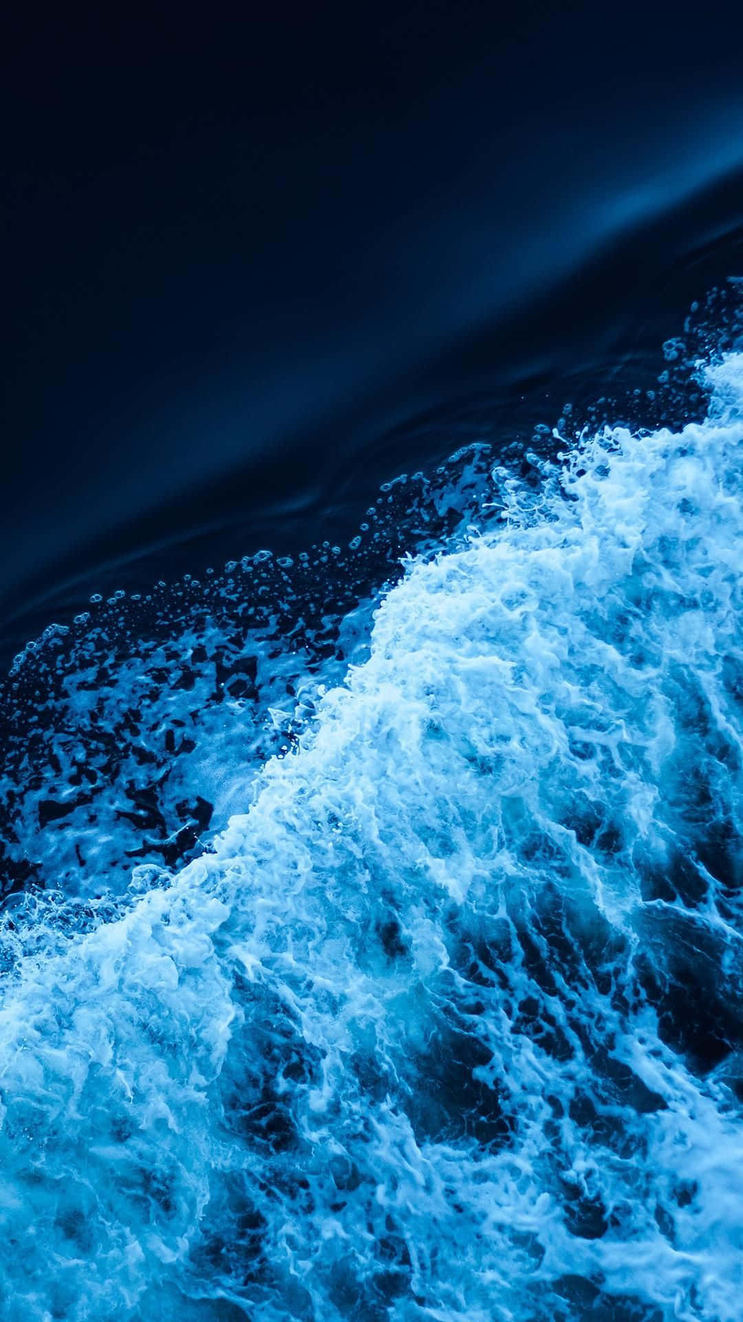 海洋 桌布 壁紙 — 動態特寫，泡沫海浪在戲劇性燈光下衝擊深藍色海水。