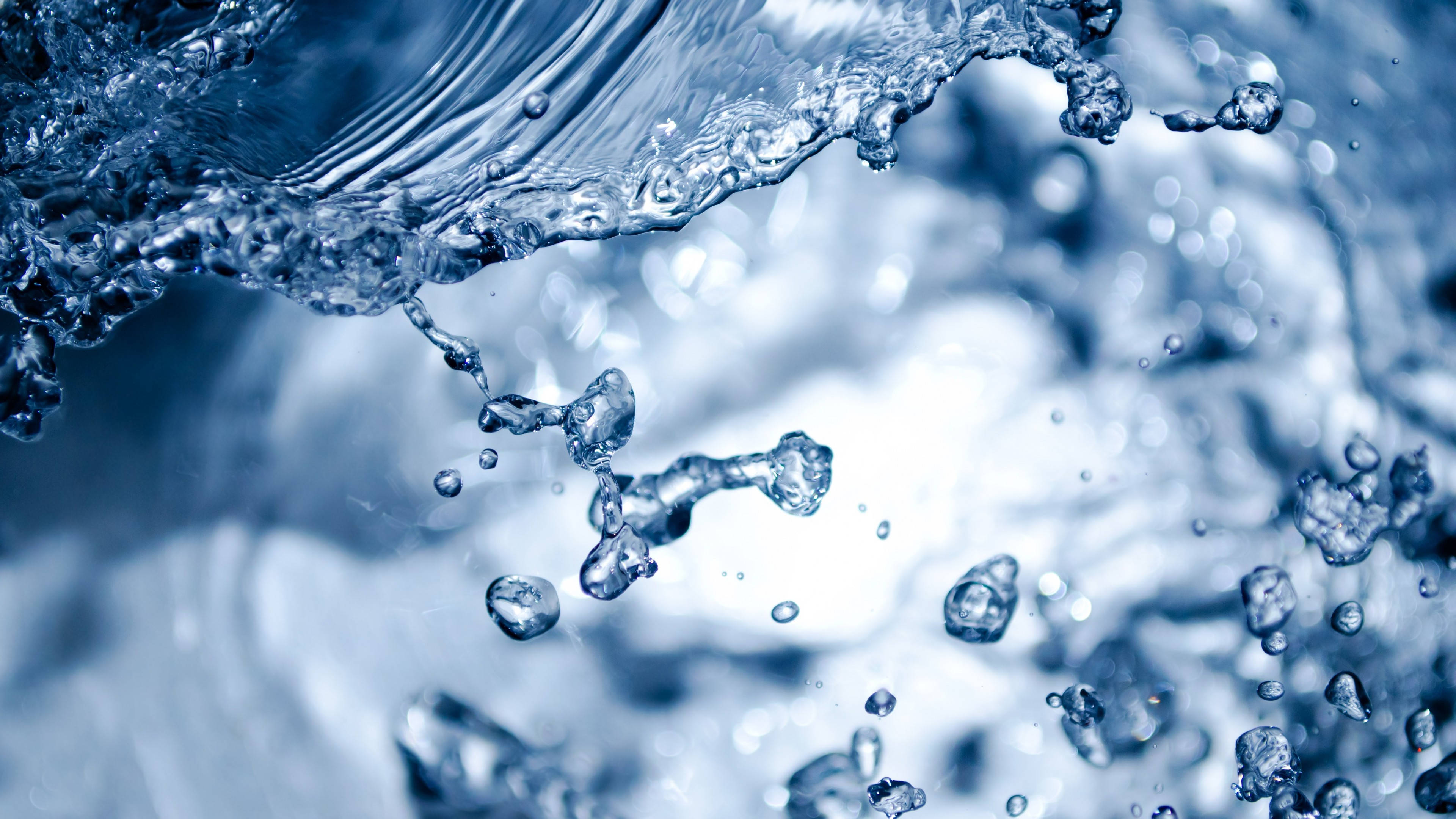 Water Splash 桌布 壁紙 — 動態特寫藍色水花飛濺，水滴懸浮在半空中，背景模糊。