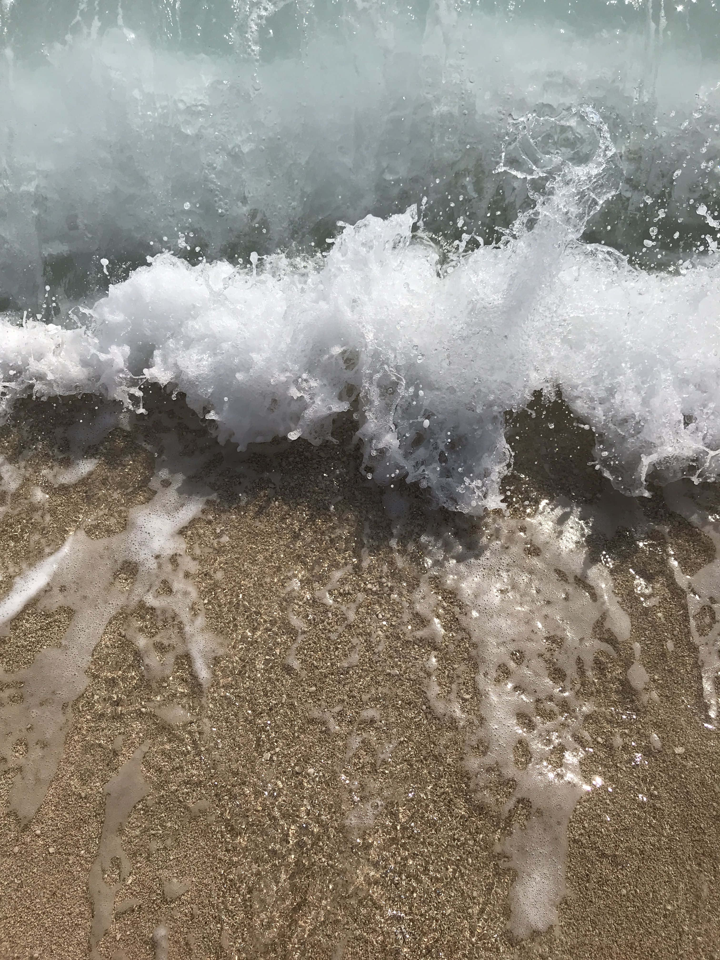白色美學動圖 桌布 壁紙 — 動態的海浪衝擊濕潤的金色沙灘，產生泡沫狀的白色浪花和閃閃發光的水滴。