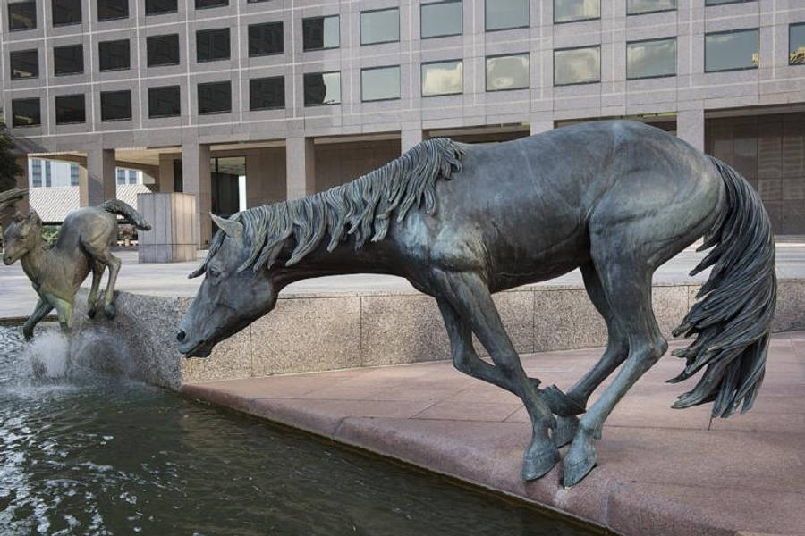 Running Horse 桌布 壁紙 — 動態青銅馬雕像在城市噴泉中疾馳，背景為現代建築。