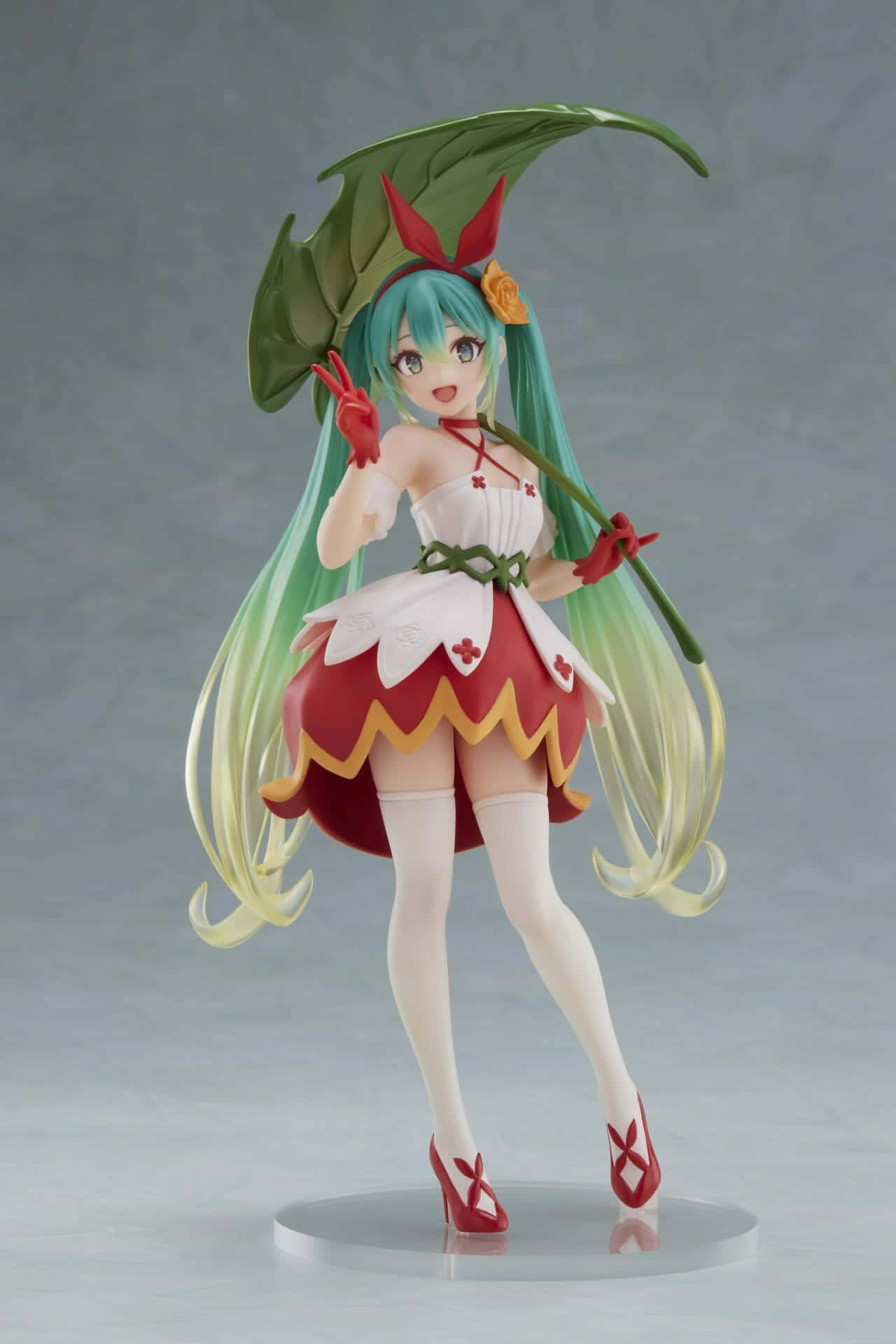 初音未來 桌布 壁紙 — 動漫公仔，一個開朗的女孩，長長的青綠色頭髮，穿著紅白相間的花裙，戴著樹葉頭飾。