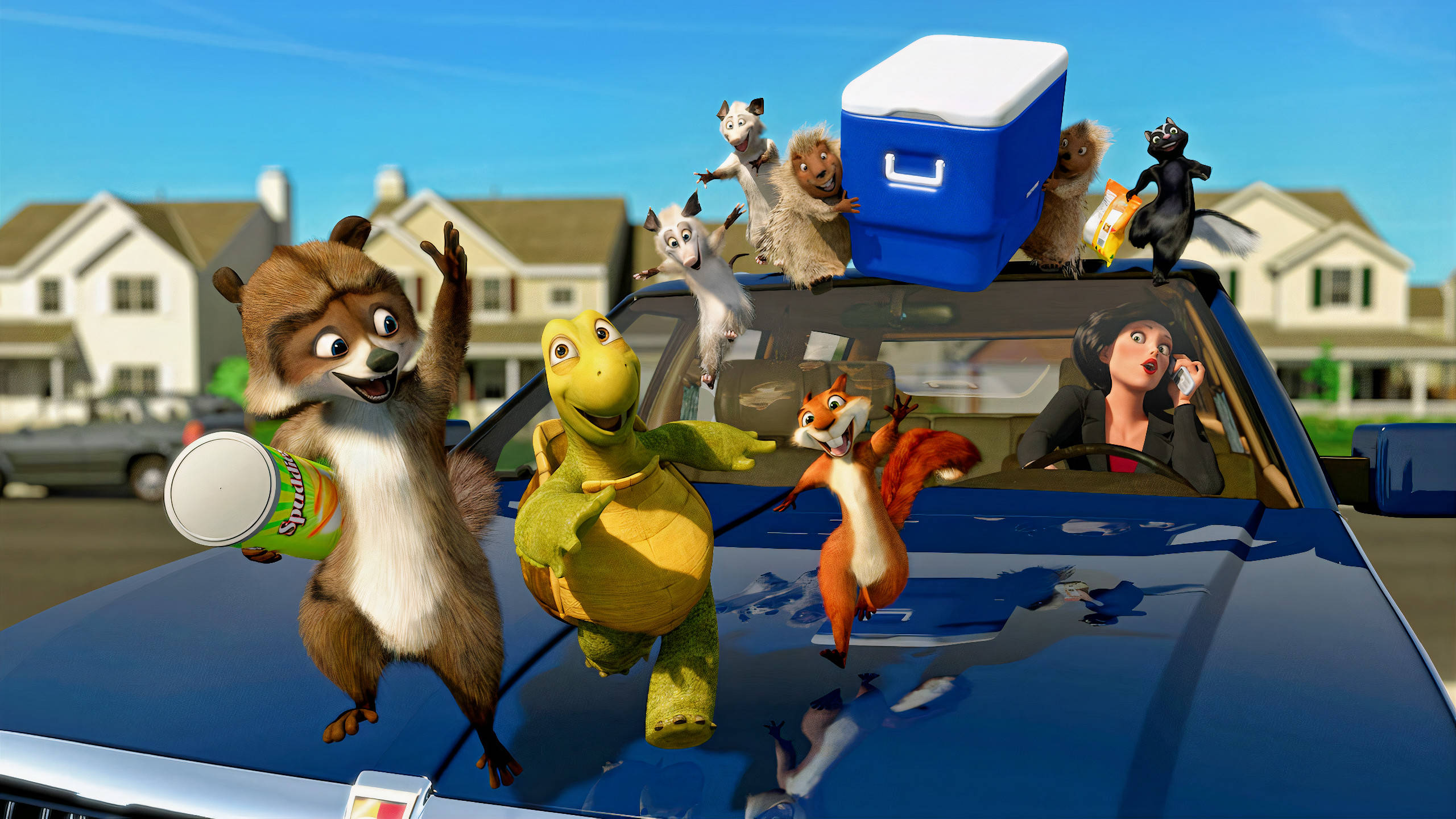 Over The Hedge 桌布 壁紙 — 動畫動物角色在晴朗藍天下的郊區社區中，與女司機一起快樂地乘坐藍色汽車。