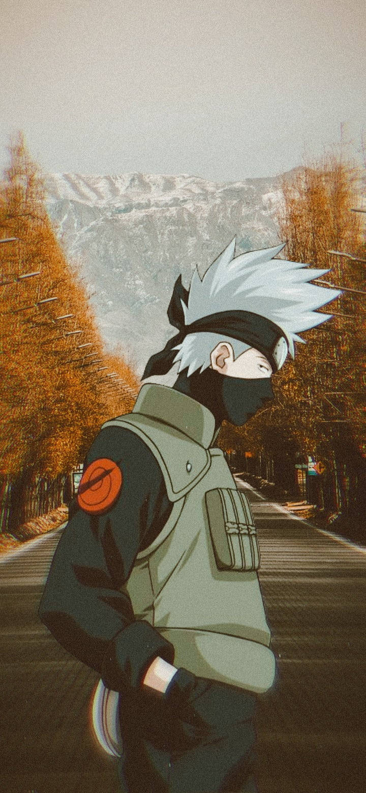 Naruto Kakashi 桌布 壁紙 — 動畫忍者，白色尖刺頭髮，戴黑色面具，站在一條兩旁有秋樹、背景有雪山的道路上。