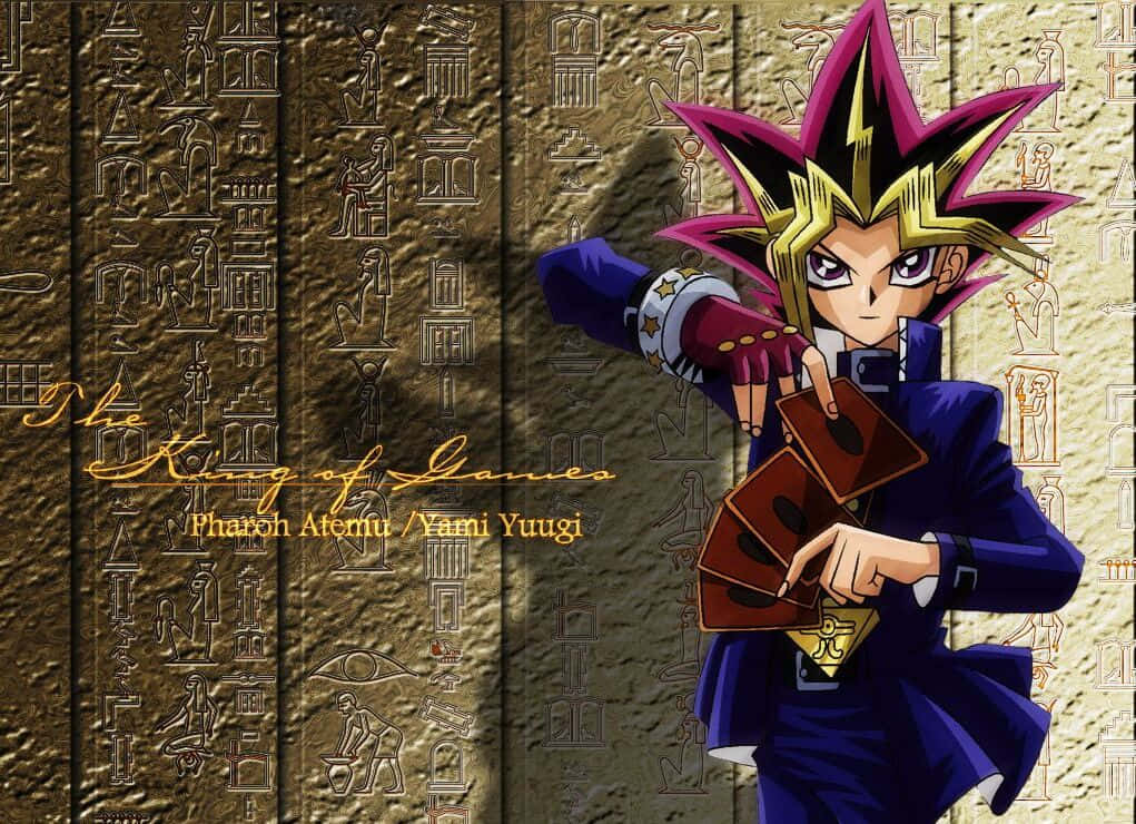 Yugi Muto 桌布 壁紙 — 動畫角色闇遊戲身穿深藍色服裝，手持卡牌，背景為古埃及象形文字牆。
