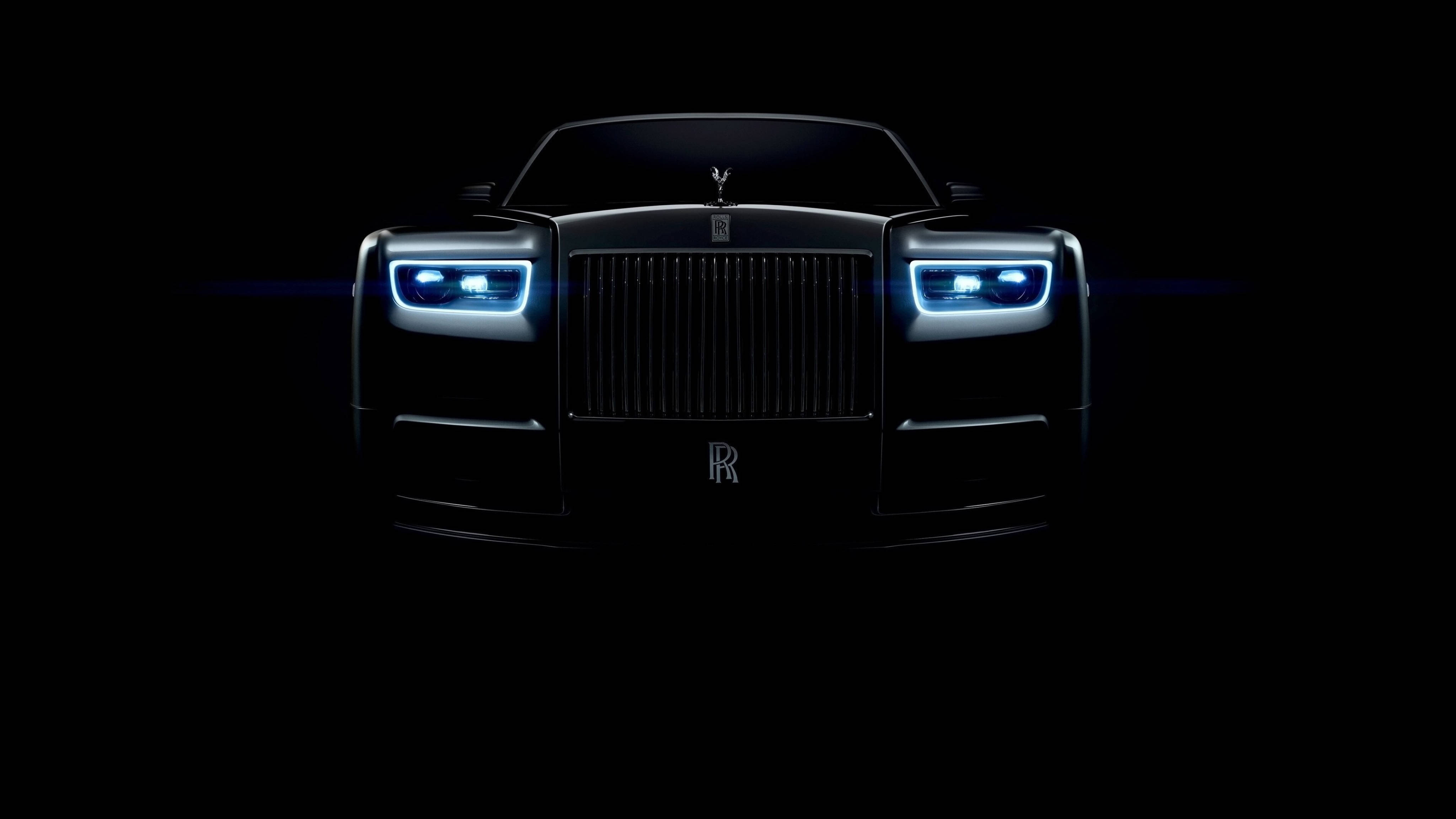 Full 4K 桌布 壁紙 — 勞斯萊斯Phantom正面視圖，由發光的藍色車頭燈照亮，背景漆黑一片。