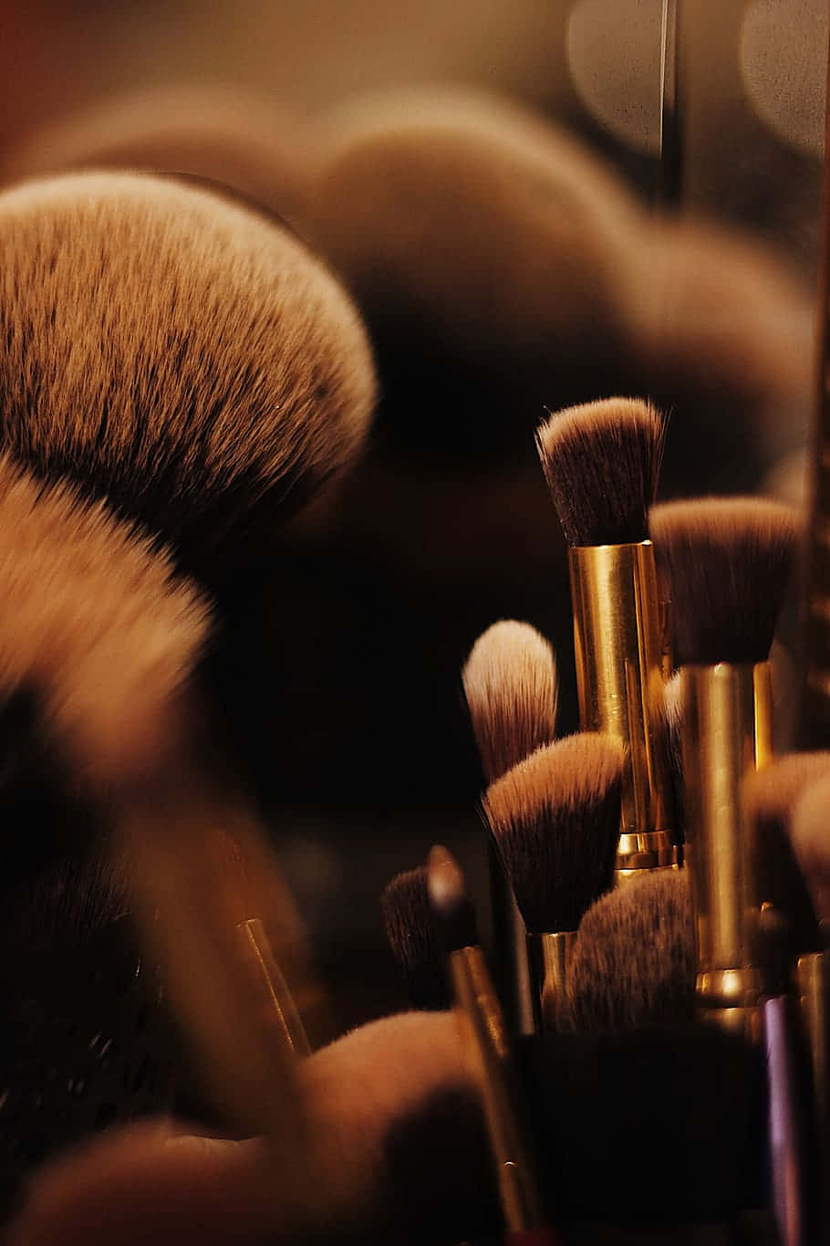 Cosmetic 桌布 壁紙 — 化妝刷特寫，金色手柄，柔軟刷毛，沐浴在溫暖的金色光線中，背景模糊。
