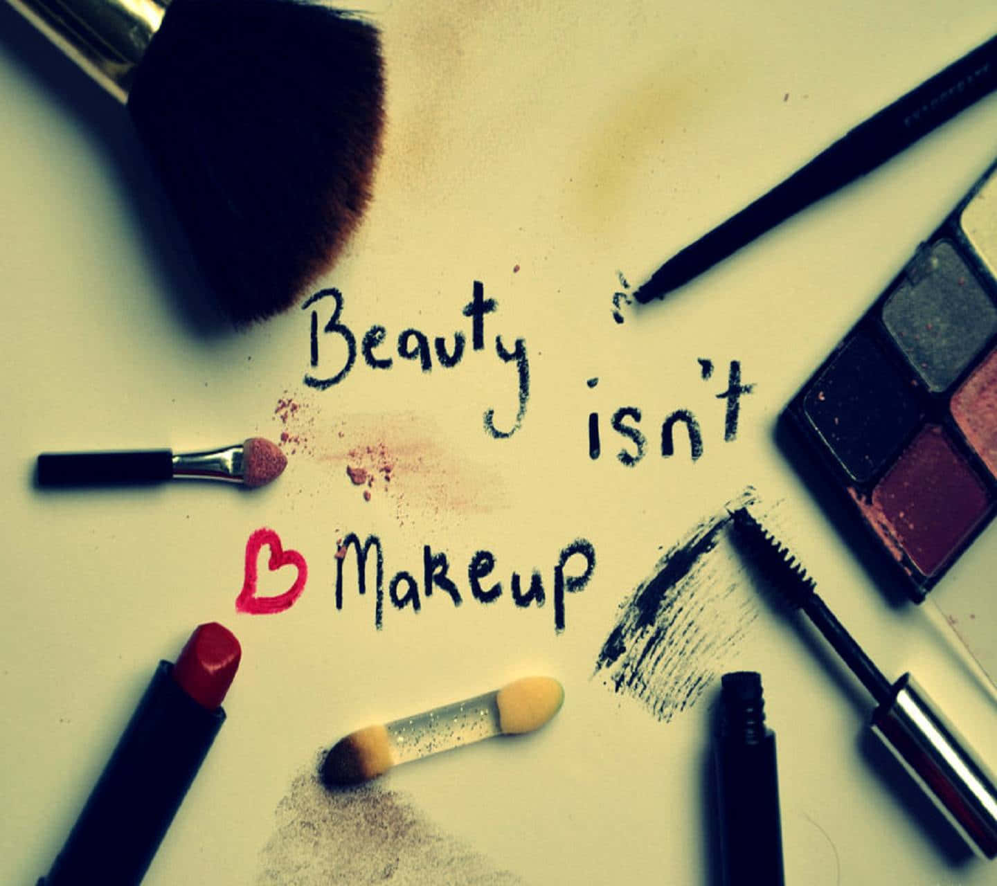 彩妝 桌布 壁紙 — 化妝工具和產品散落在手寫文字「Beauty isn't Makeup」周圍，並有一個紅色心形。