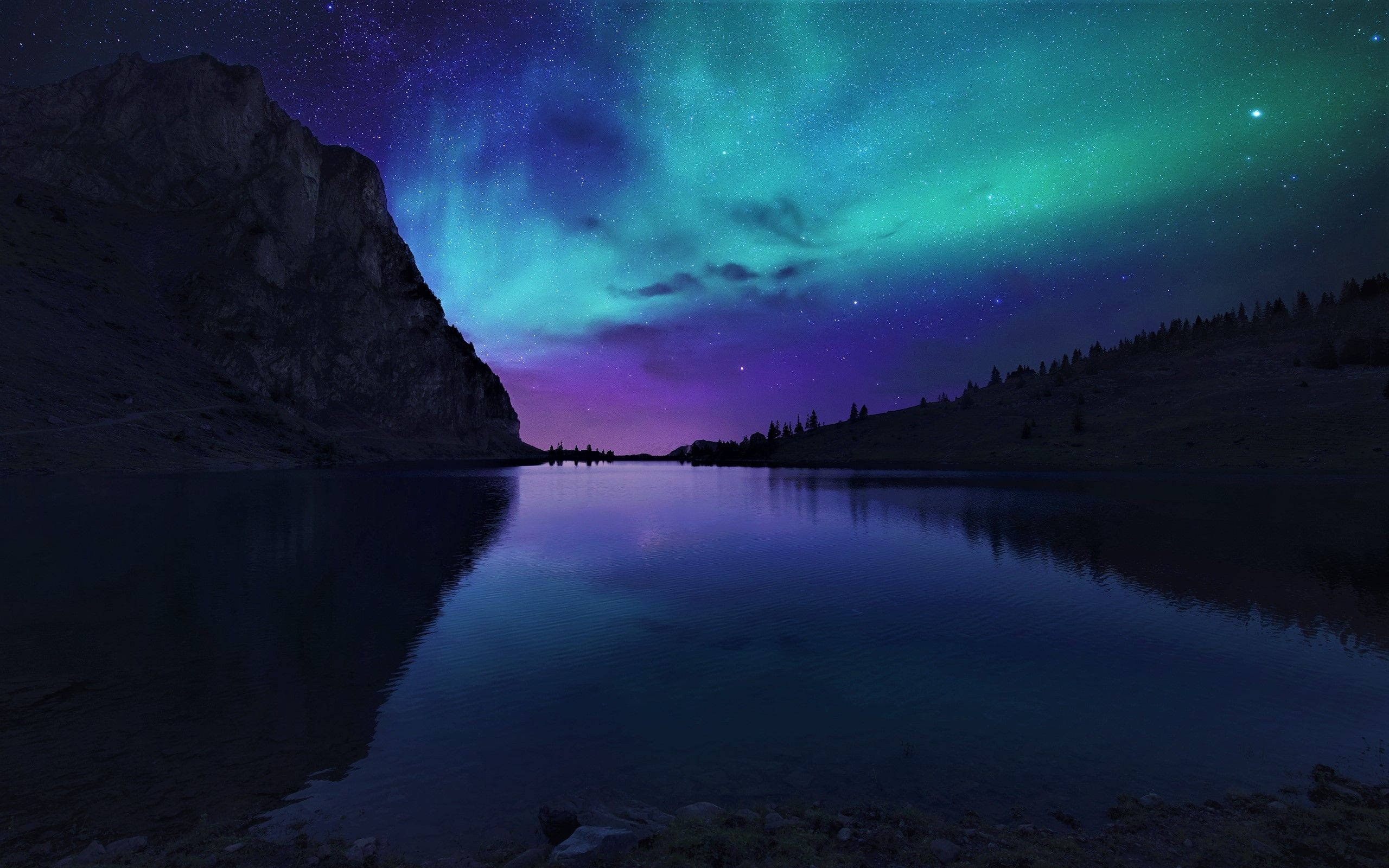 lights 桌布 壁紙 — 北極光以鮮豔的綠色和紫色在星空夜空中舞動，倒映在寧靜的山間湖泊中。