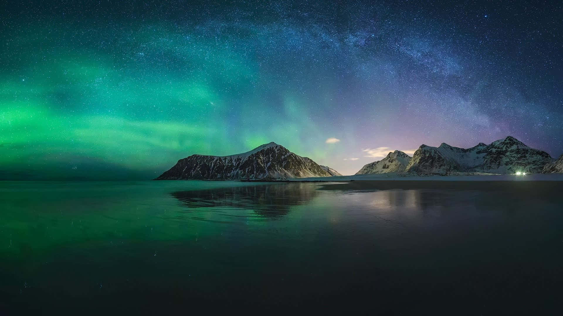 極光 桌布 壁紙 — 北極光在繁星點點的夜空上以鮮綠色舞動，映照在平靜水面上的雪山之上。