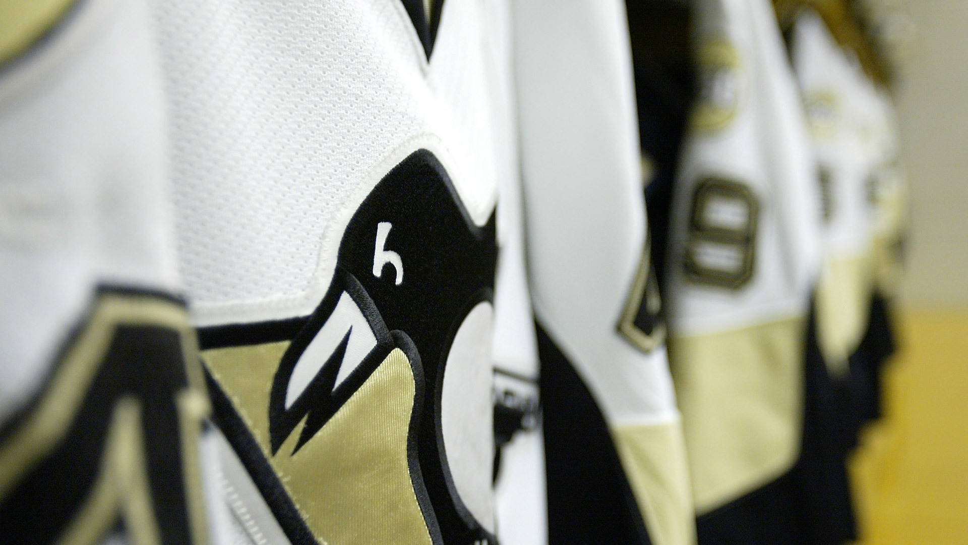 penguins 桌布 壁紙 — 匹茲堡企鵝冰球球衣掛成一排的特寫，清晰對焦在標誌和6號上。