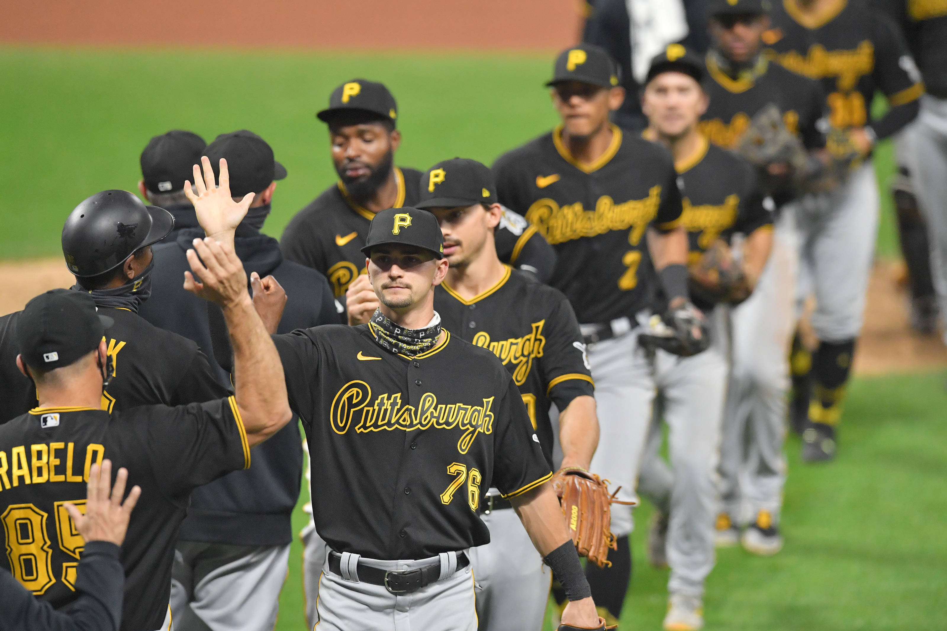 Pittsburgh Pirates 桌布 壁紙 — 匹茲堡棒球選手身穿黑金球衣，在球場燈光下的綠色草地上擊掌慶祝。