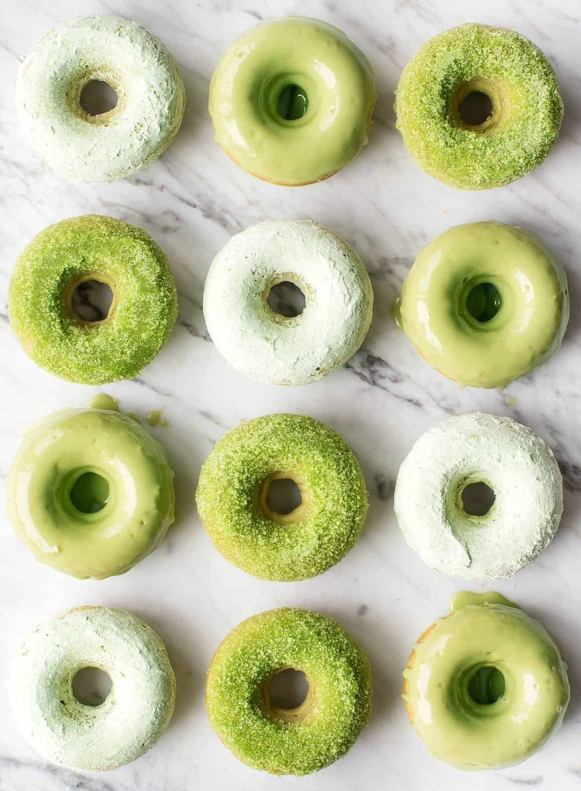 Donut 桌布 壁紙 — 十二個抹茶糖霜甜甜圈，撒上糖粉，整齊排列在白色大理石表面上。