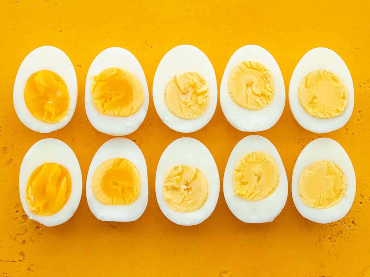 Eggs 桌布 壁紙 — 十個半邊水煮蛋整齊排列在充滿活力的橙色紋理表面上。