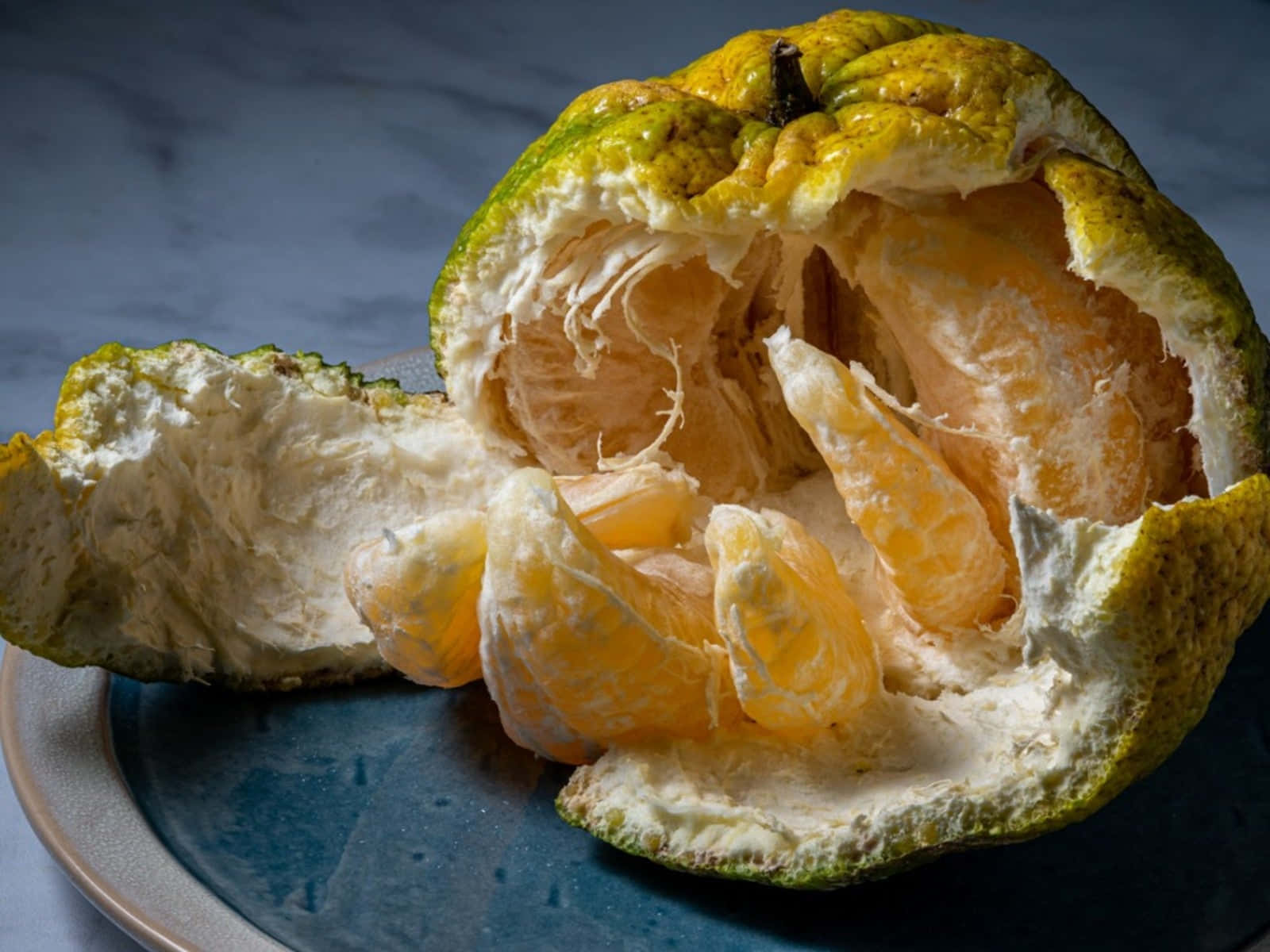 Fruits 桌布 壁紙 — 半個切開、帶有紋理的柑橘類水果，多汁的橙肉放在藍色盤子上，背景是大理石。