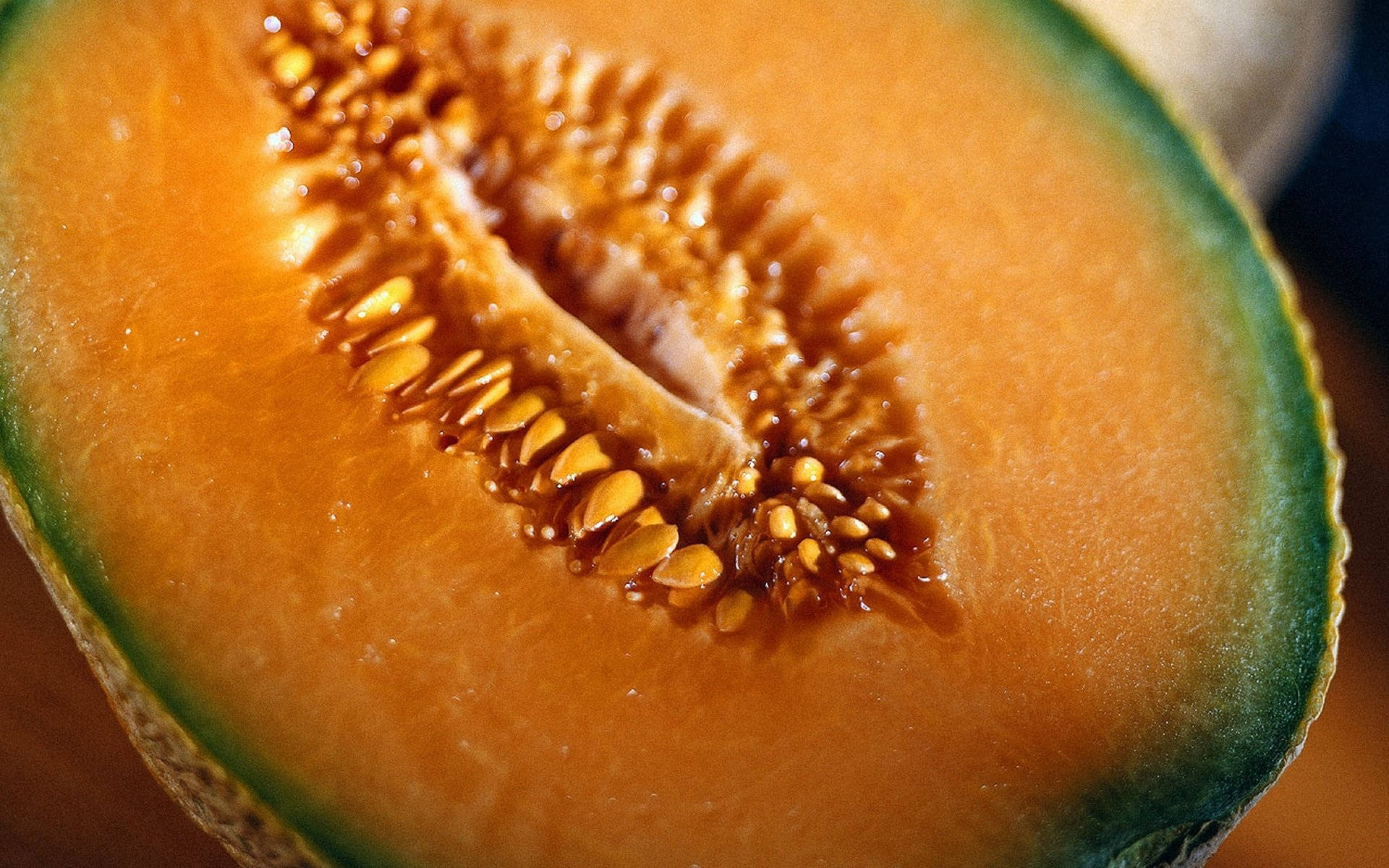 Fruit 桌布 壁紙 — 半個哈密瓜的特寫，露出多汁的橙色果肉和充滿種子的中央空腔。