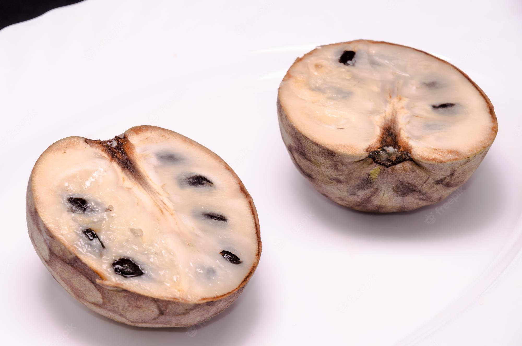 iPhone 桌布 壁紙 — 半個星蘋果水果切開，露出奶油白色果肉，上面有黑色種子，放在白色盤子上。