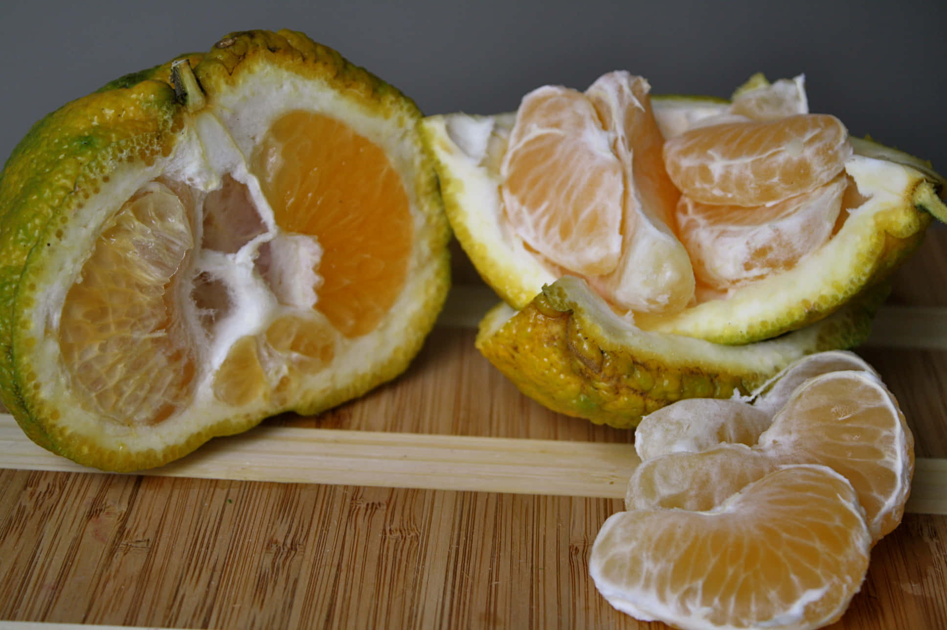 Fruits 桌布 壁紙 — 半個柑橘類水果，帶有鮮豔的橙色果肉和白色果皮，放在木製砧板上。