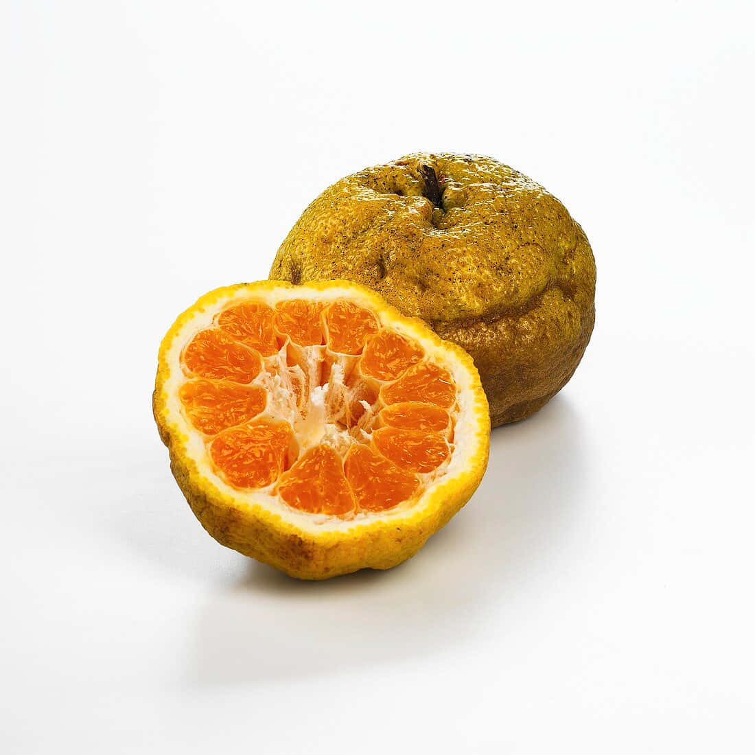 Fruits 桌布 壁紙 — 半個柑橘類水果，帶有鮮豔的橙色果肉和凹凸不平的果皮，放在潔白的表面上，旁邊是一個完整的水果。