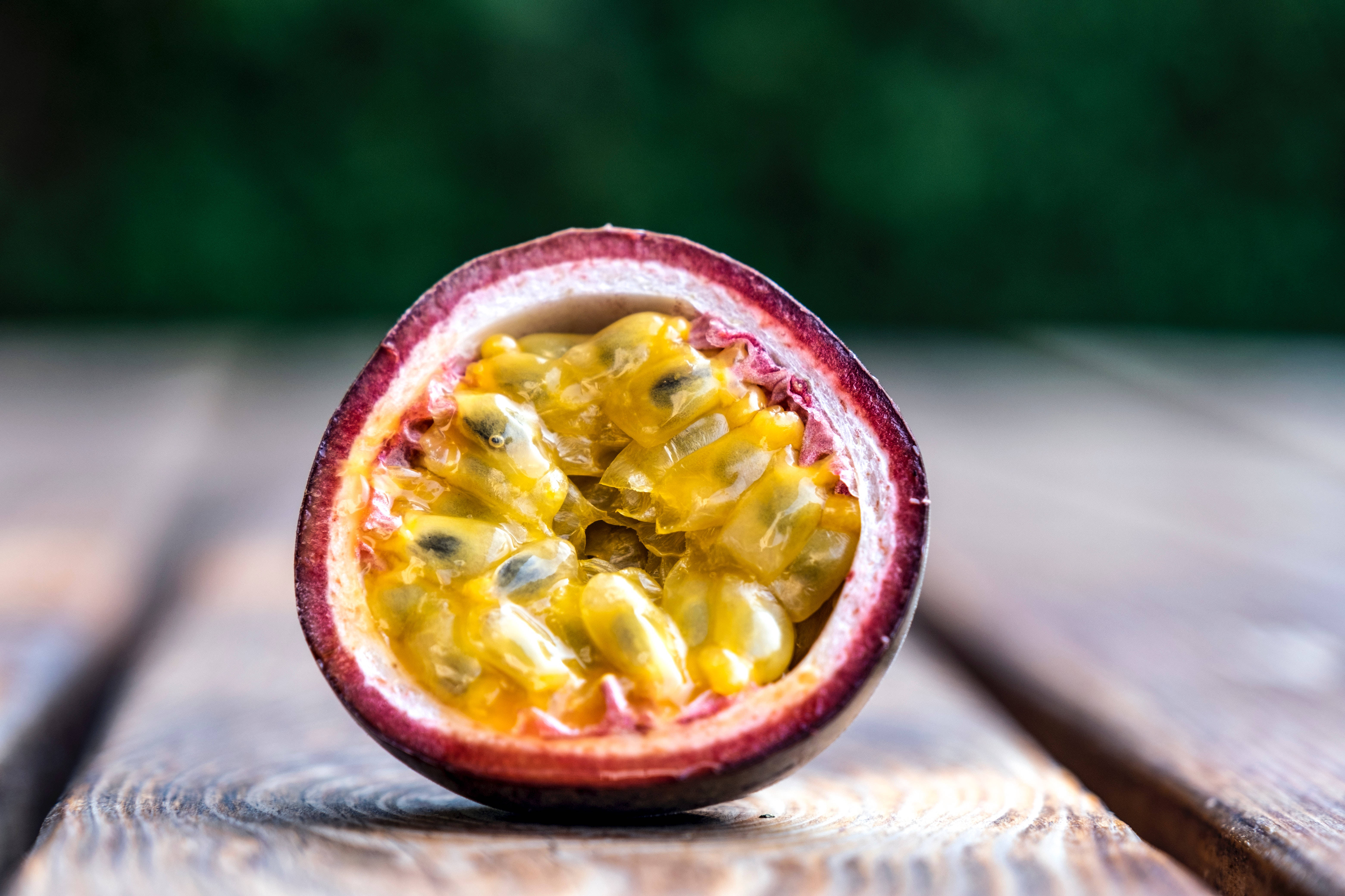 Fruit 桌布 壁紙 — 半個百香果露出多汁的黃色果肉和黑色種子，放在經風化的木質表面上。