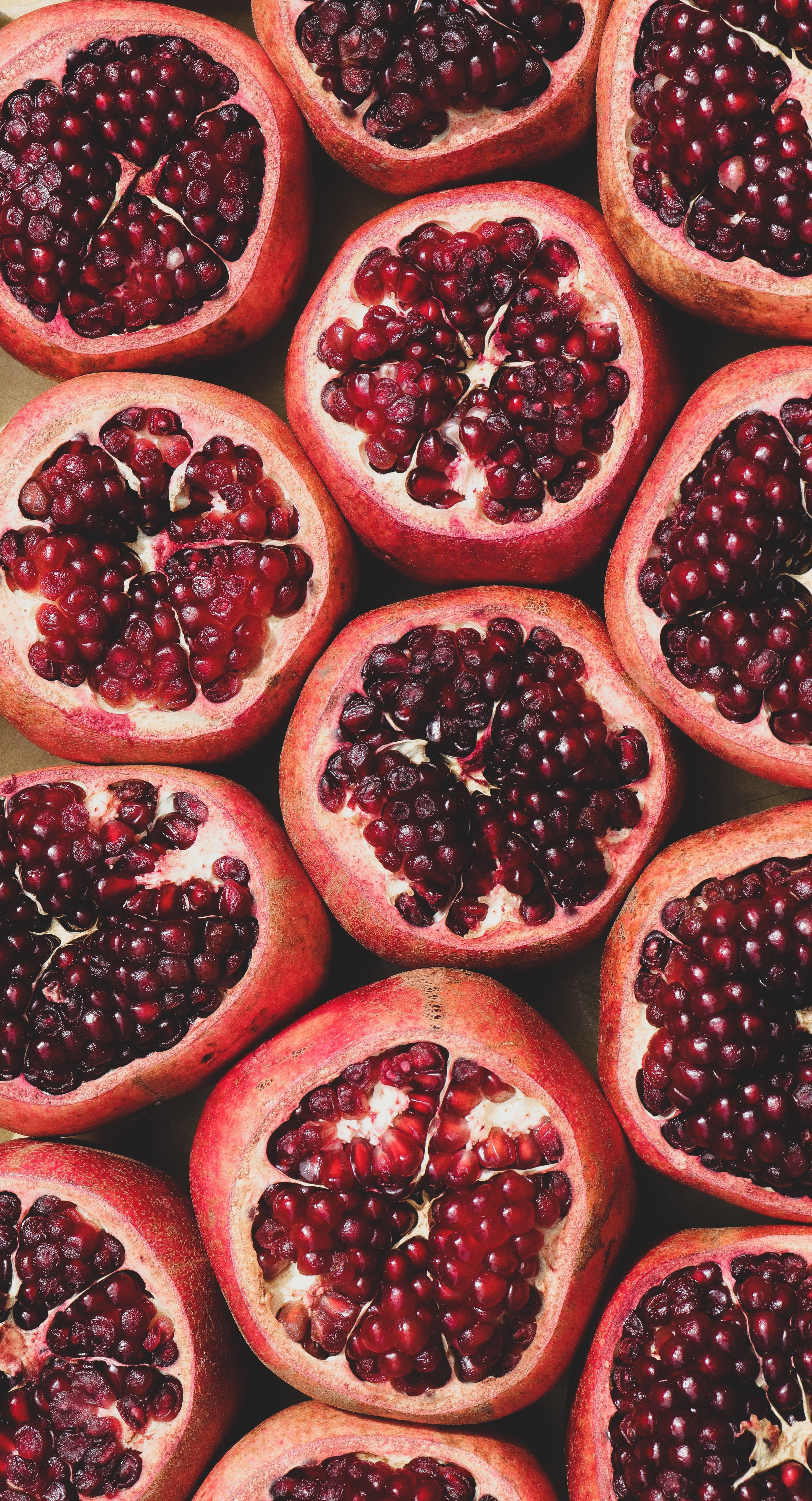 Fruits 桌布 壁紙 — 半個石榴的特寫，露出多汁的紅寶石色果粒，襯著粉紅色的果皮。