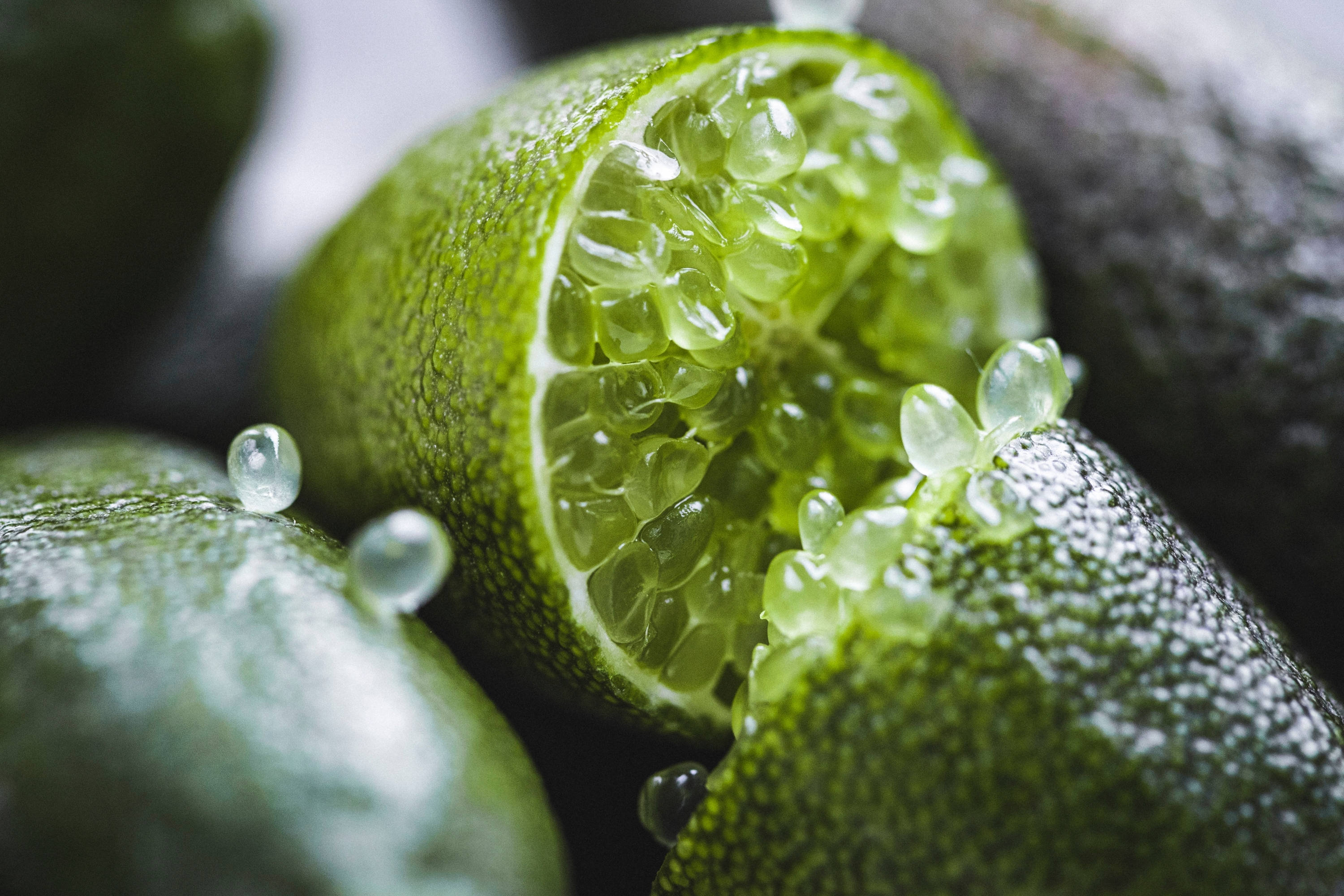 Fruits 桌布 壁紙 — 半個萊姆的特寫，露出閃閃發光的半透明果肉，水滴附著在紋理清晰的綠色外皮上。
