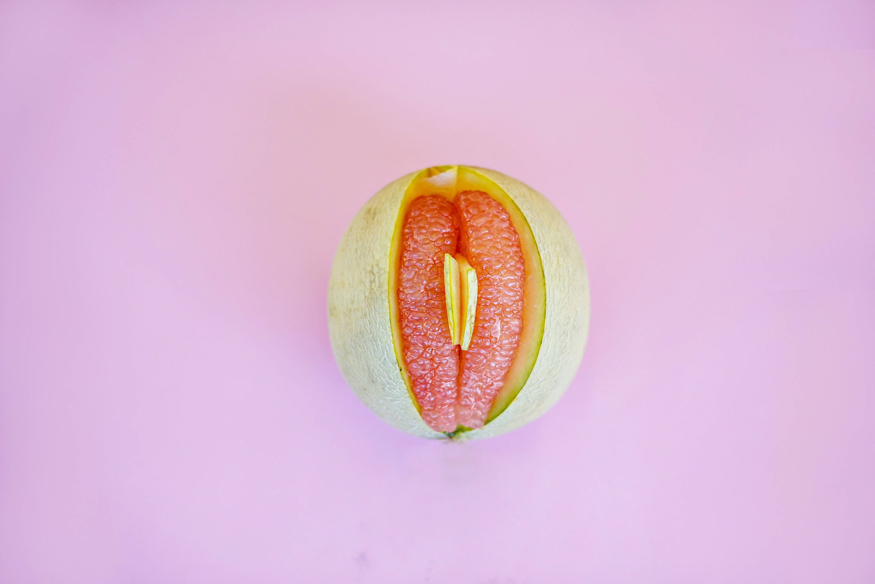 Fruit 桌布 壁紙 — 半個葡萄柚露出多汁的粉紅色果肉，襯托著柔和的粉紅色背景。