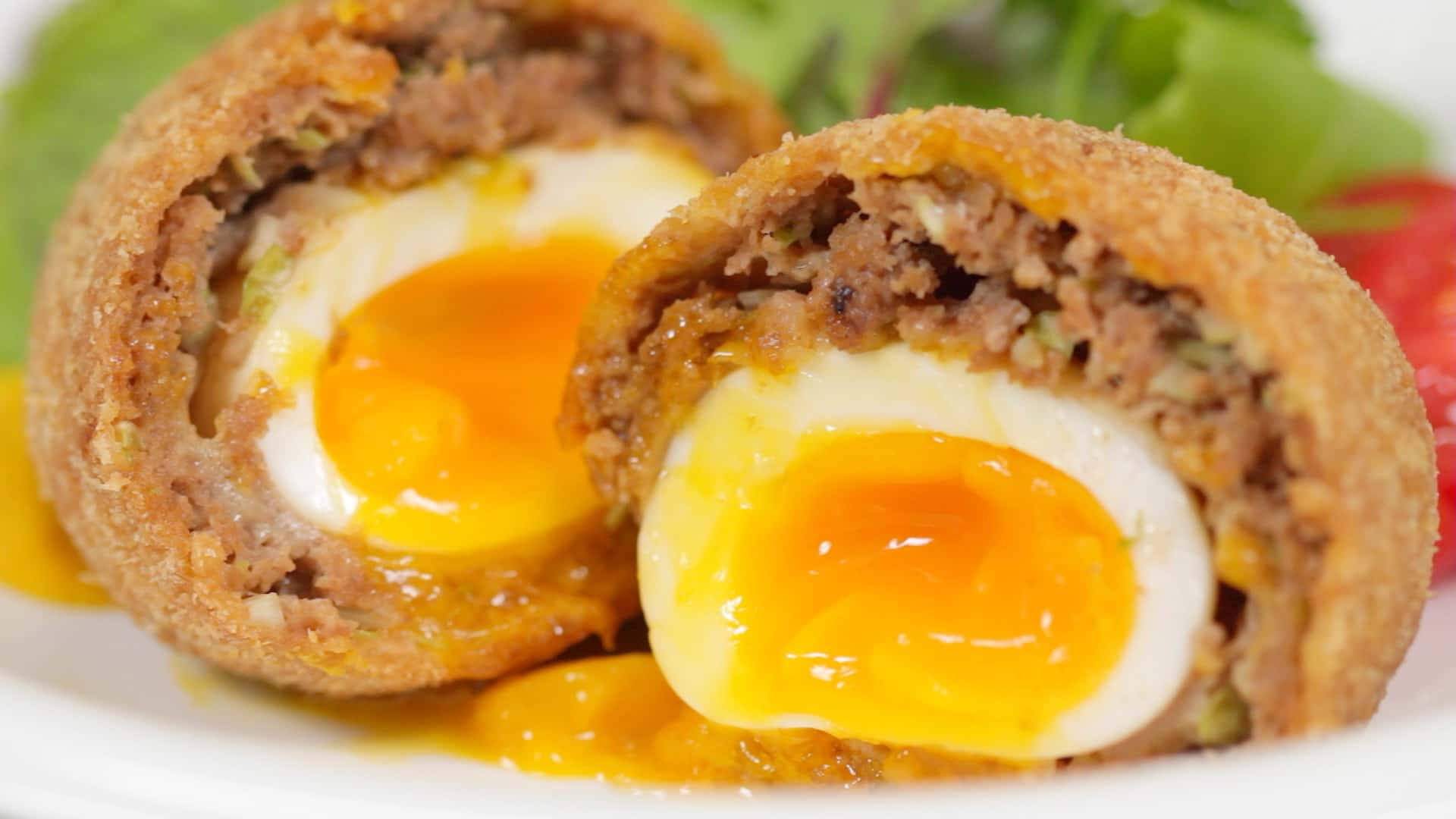 Egg 桌布 壁紙 — 半個蘇格蘭蛋的特寫，露出流心蛋黃和酥脆的麵包糠外層。