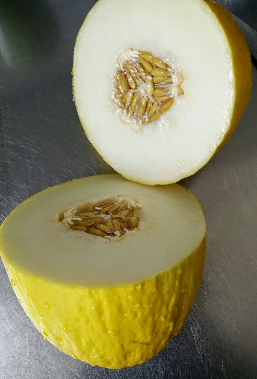 Fruit 桌布 壁紙 — 半個黃色蜜瓜，果肉淡白帶籽，放在拉絲金屬表面上。