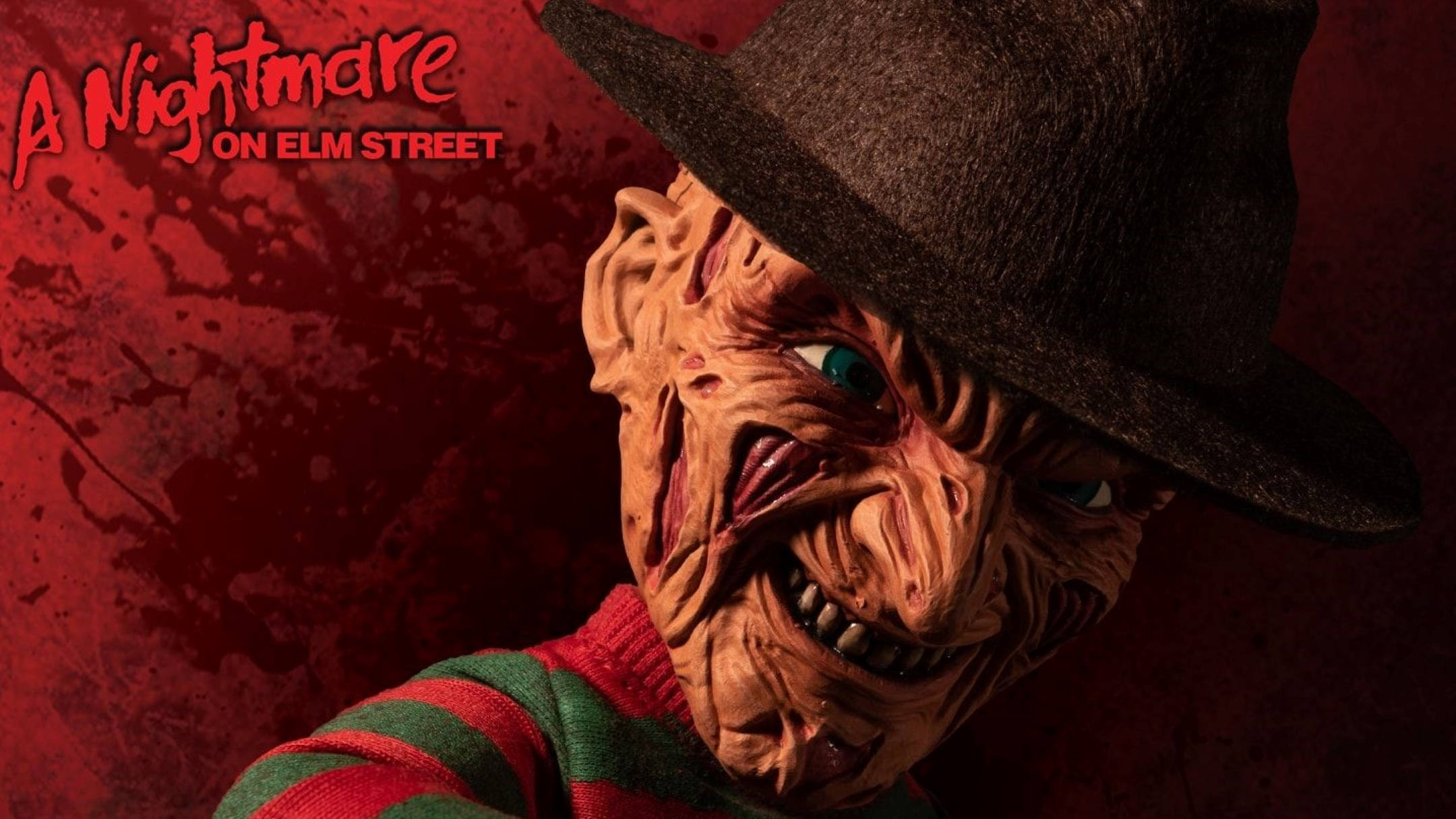 Freddy 桌布 壁紙 — 《半夜鬼上床》中的佛萊迪·克魯格在血跡斑斑的紅色背景前，帶著邪惡的笑容，威脅地凝視著。