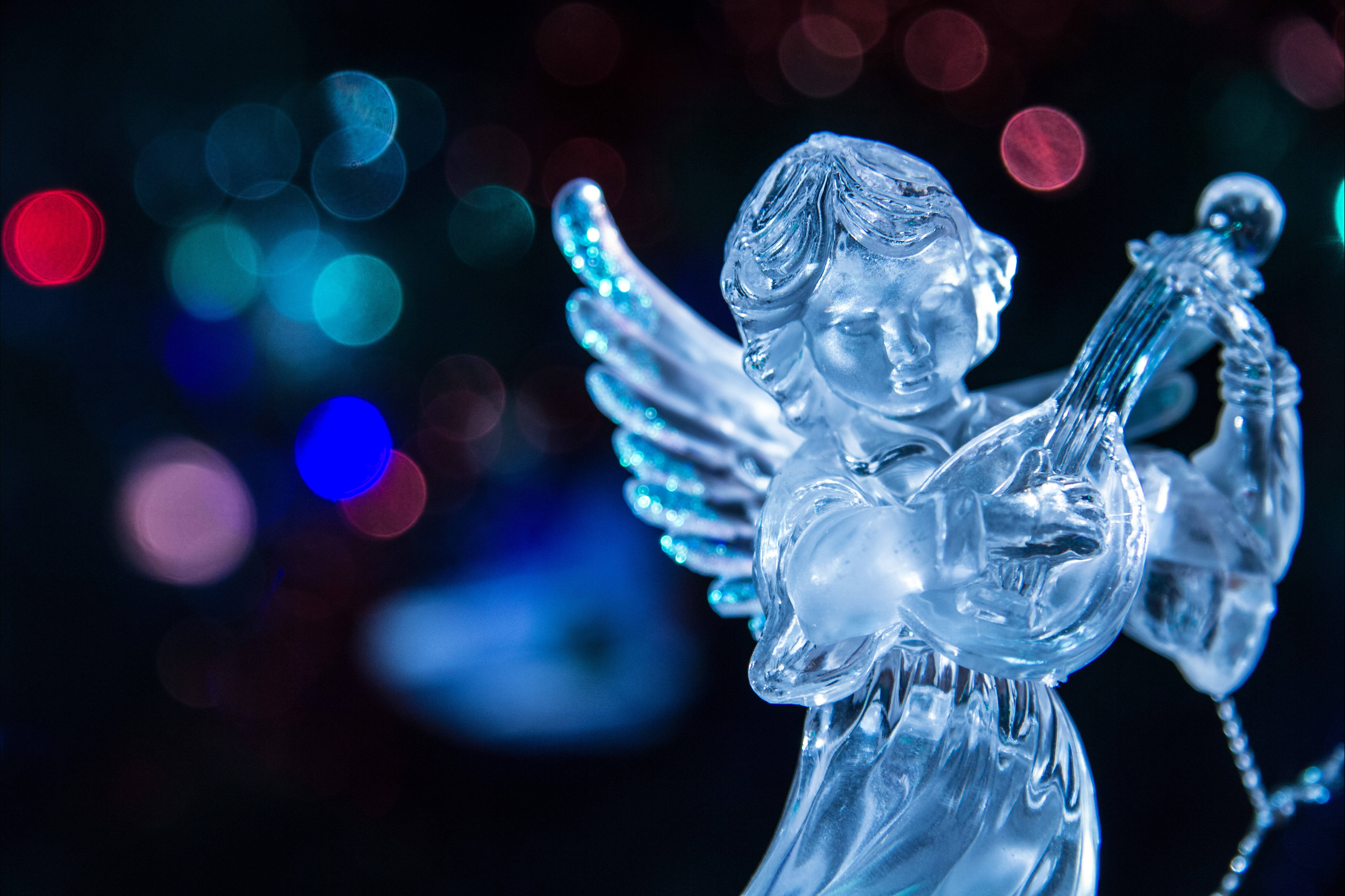 angels 桌布 壁紙 — 半透明玻璃天使雕像在色彩繽紛的散景燈光背景下彈奏豎琴。