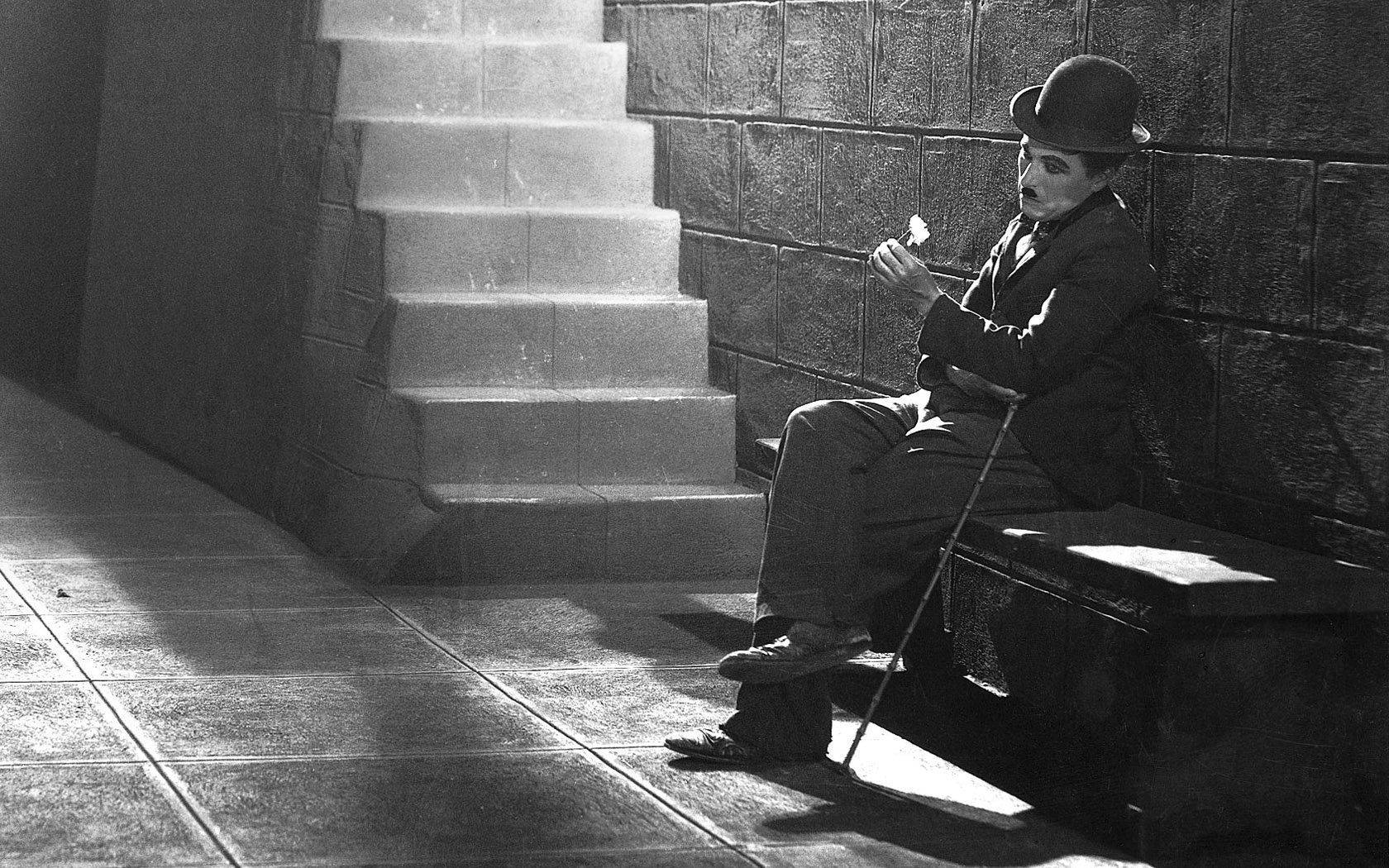 Chaplin 桌布 壁紙 — 卓別林獨自坐在石階旁的長椅上，身處一個黑白分明的城市小巷。