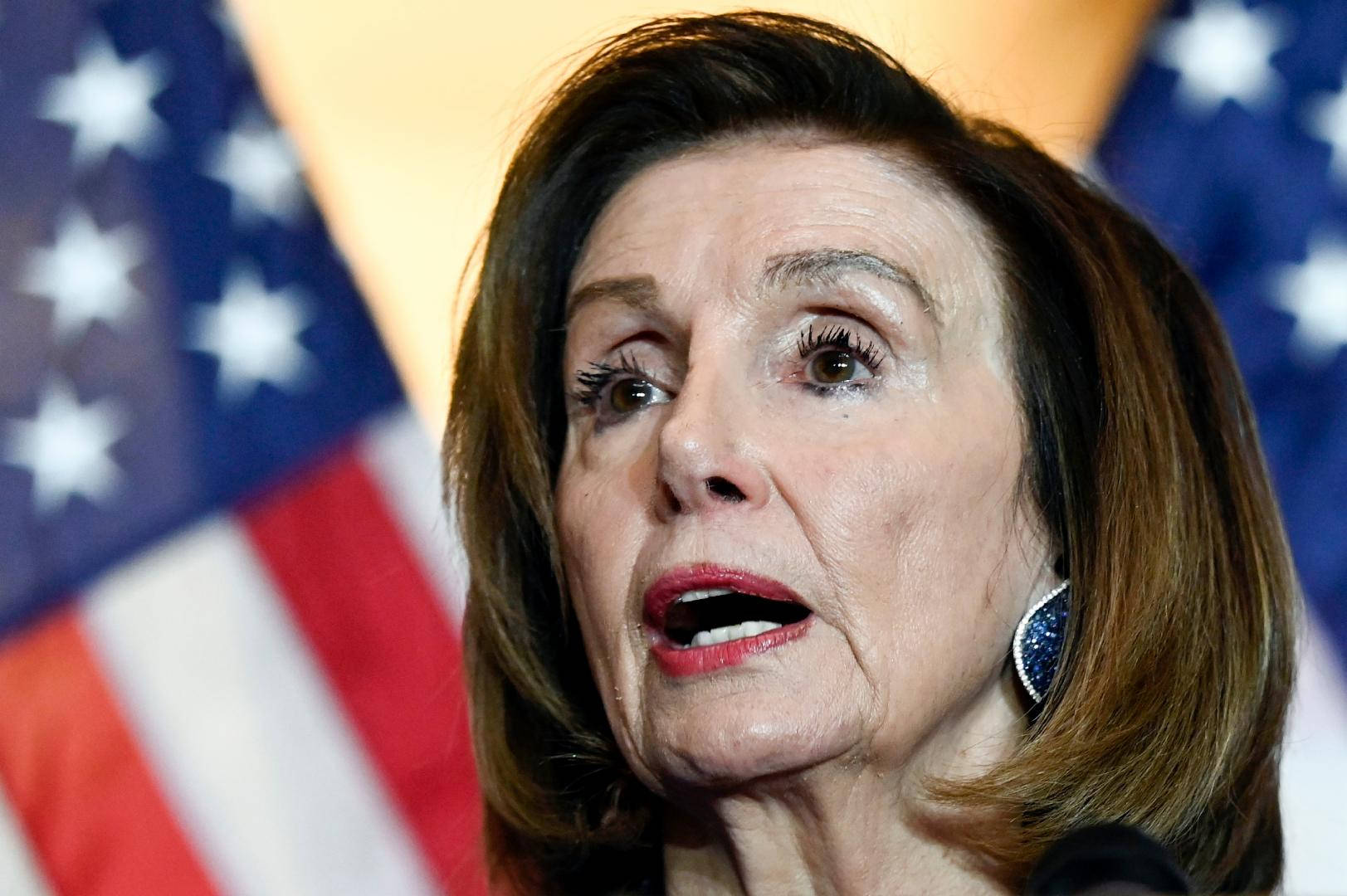 Nancy Pelosi 桌布 壁紙 — 南希·佩洛西在模糊的美國國旗背景下激烈演講的特寫。