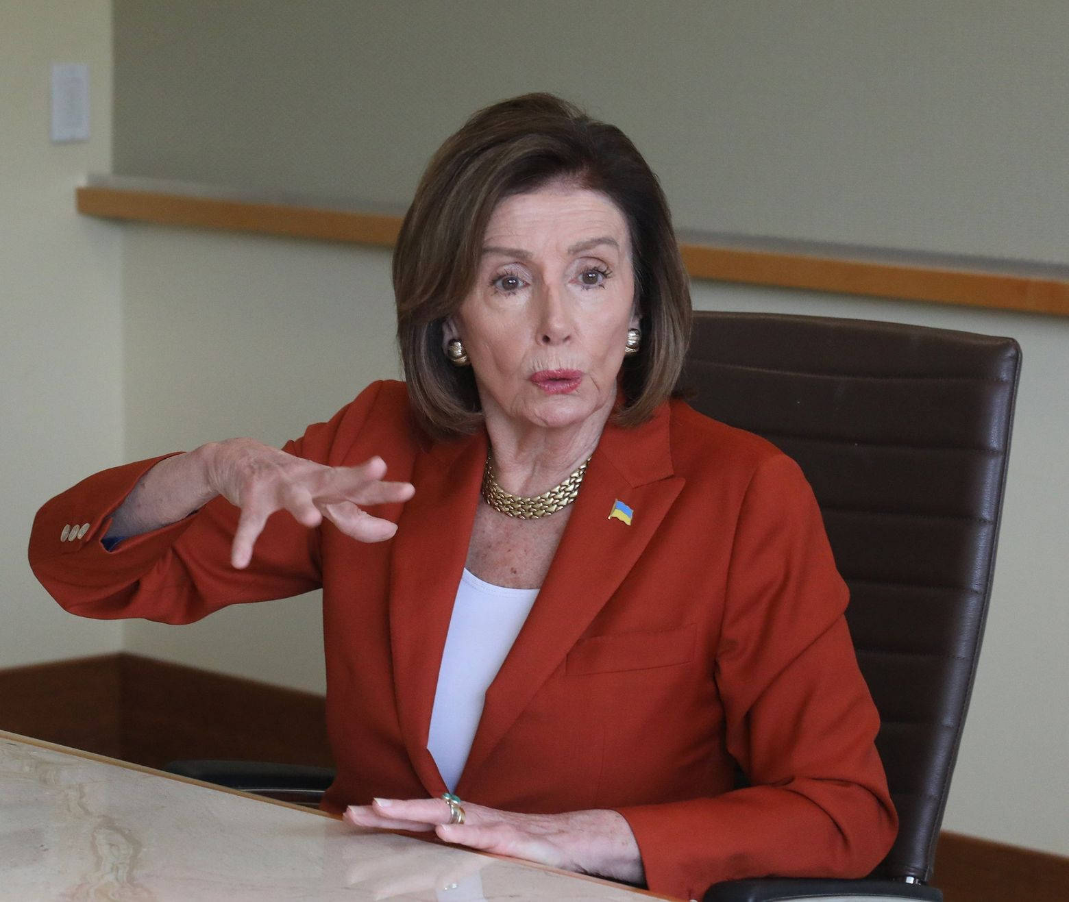 Nancy Pelosi 桌布 壁紙 — 南希·裴洛西坐在辦公桌前，在正式的辦公室環境中說話時做手勢。