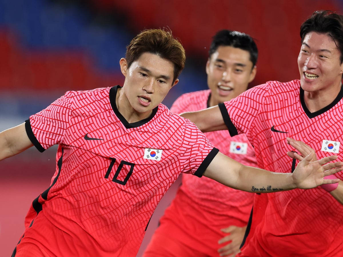 Football Players 桌布 壁紙 — 南韓足球運動員身穿紅色球衣，以強烈的表情和動態動作慶祝進球。