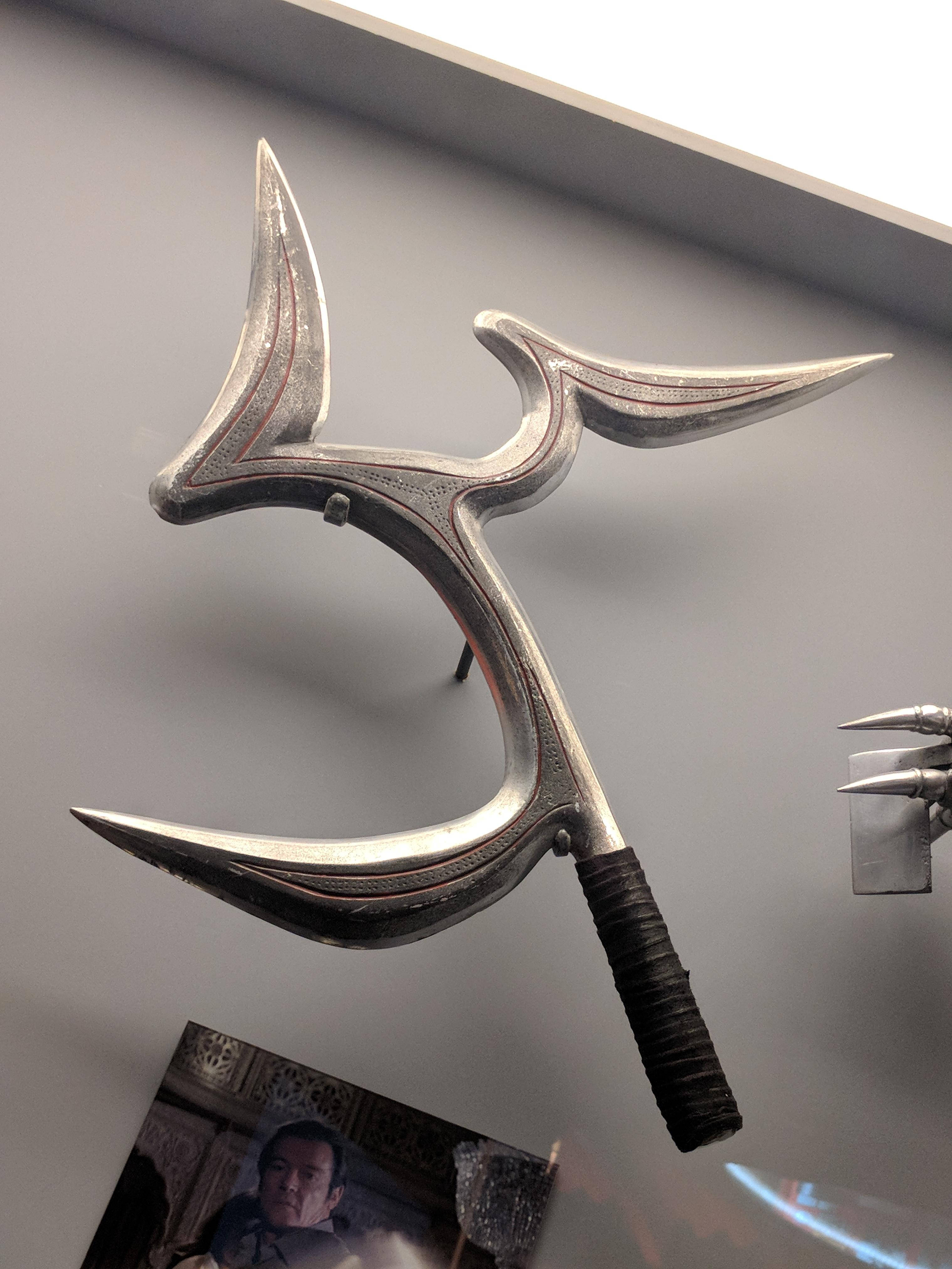 Boomerang 桌布 壁紙 — 博物館展覽中，灰色牆上安裝的時尚銀色裝飾武器，帶有三個彎曲刀片和黑色手柄。