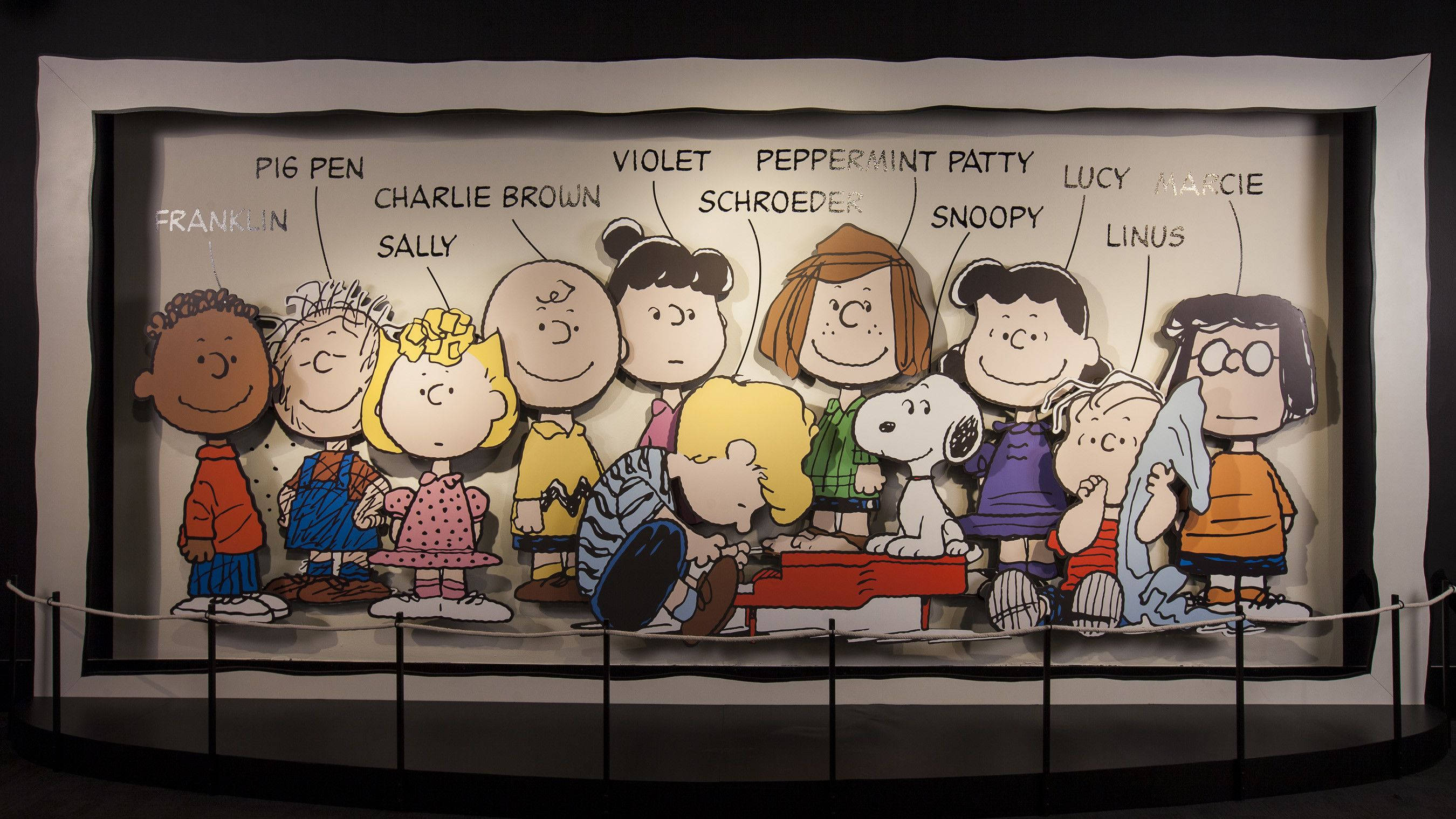 lucy 桌布 壁紙 — 博物館展覽中一個大型裱框展示，包括查理布朗、史努比和露西等經典花生漫畫角色。